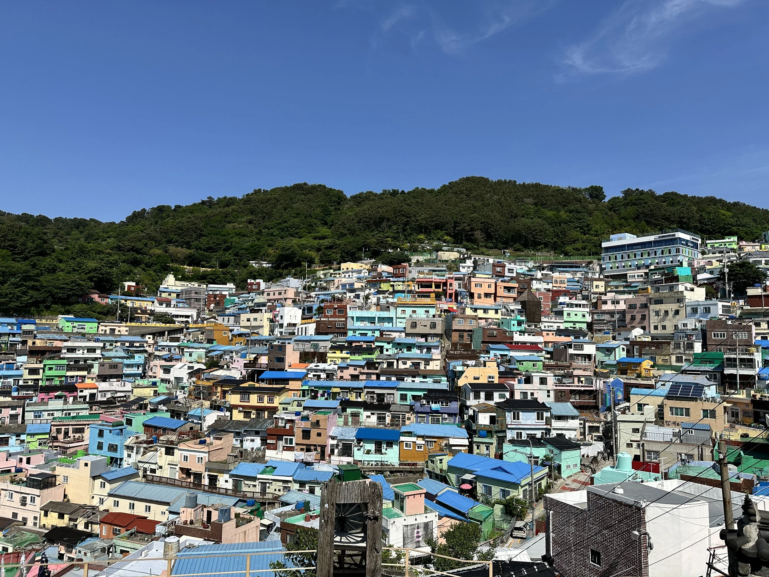 Colorful houses on a hillside with a green mountain and blue sky in the background.