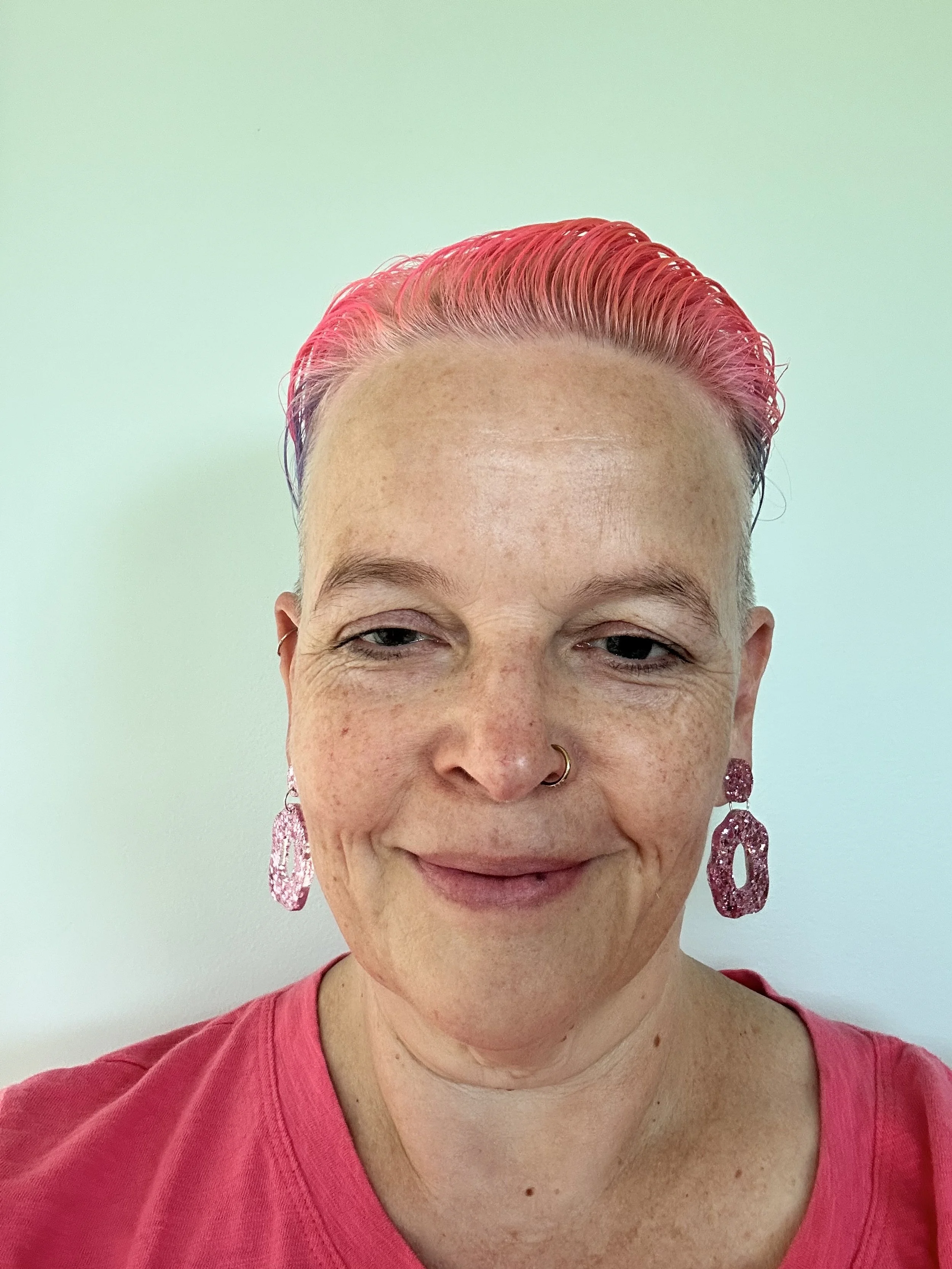 photo of Bec the Sparkly Doula. She has pink hair and sparkly earrings and a big smile.