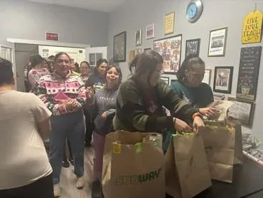 People shopping and carrying paper bags inside a store.