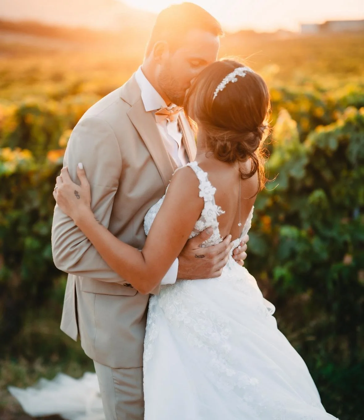 Un couple de mariés en train de s'embrasser lors d'un mariage en plein air au coucher du soleil.