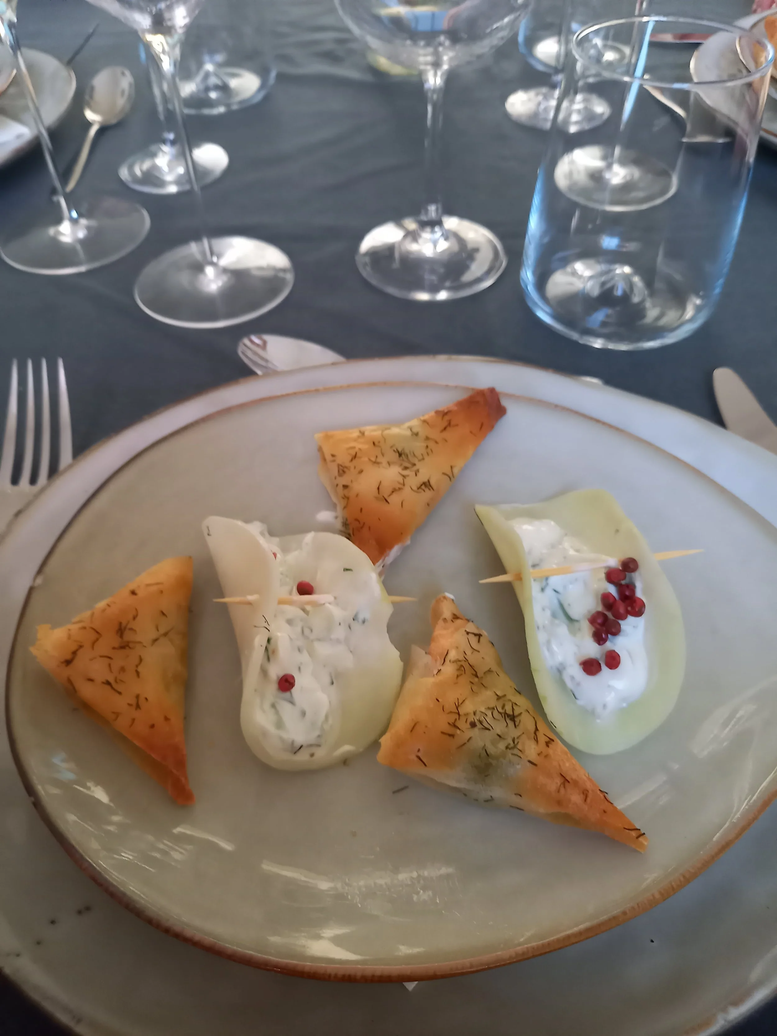 Plate de samoussas croustillants et de dips au yaourt avec garniture de graines de grains rouges.