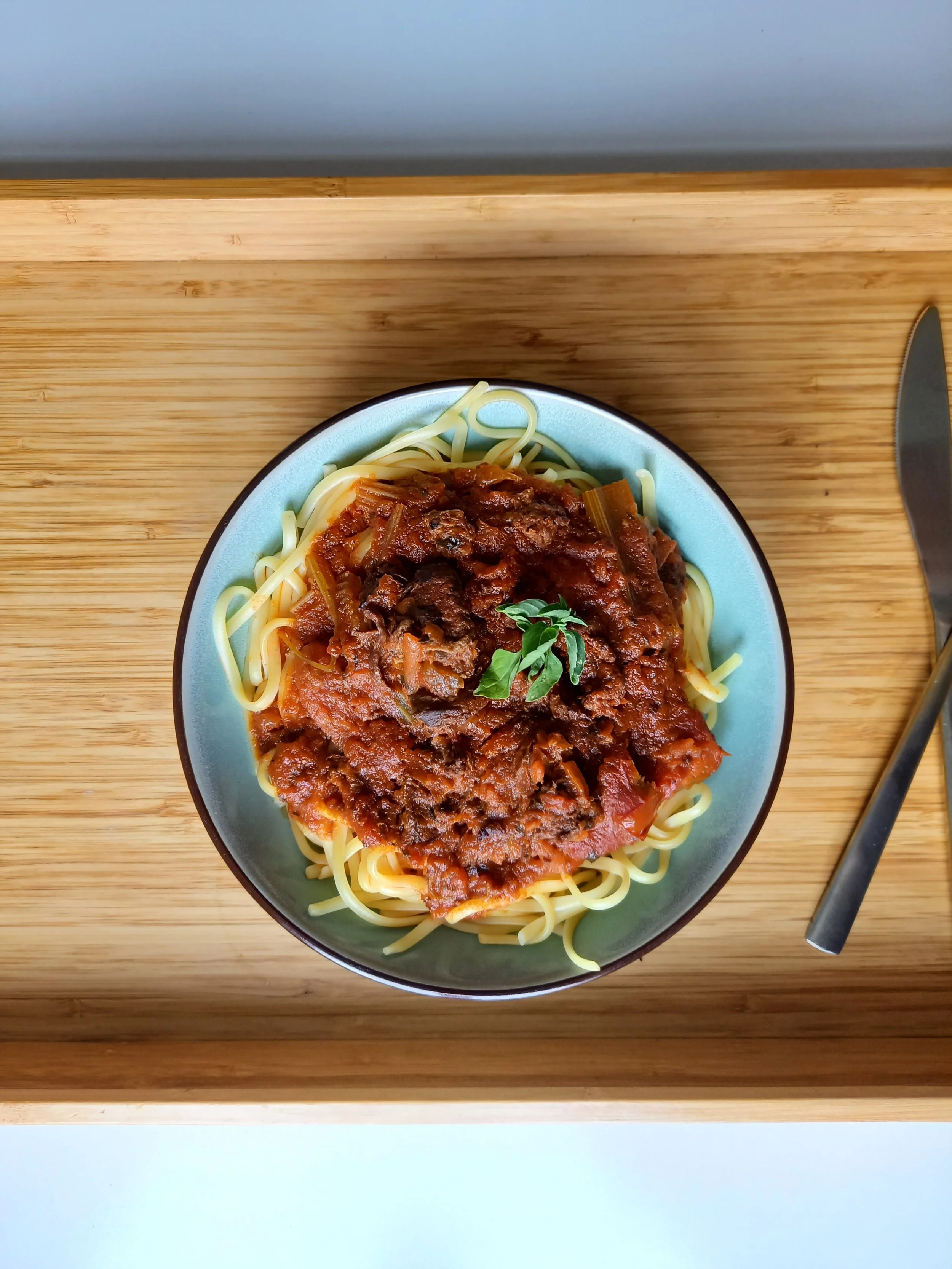 Assiette de spaghettis avec sauce bolognaise garnie de feuilles de basilic.