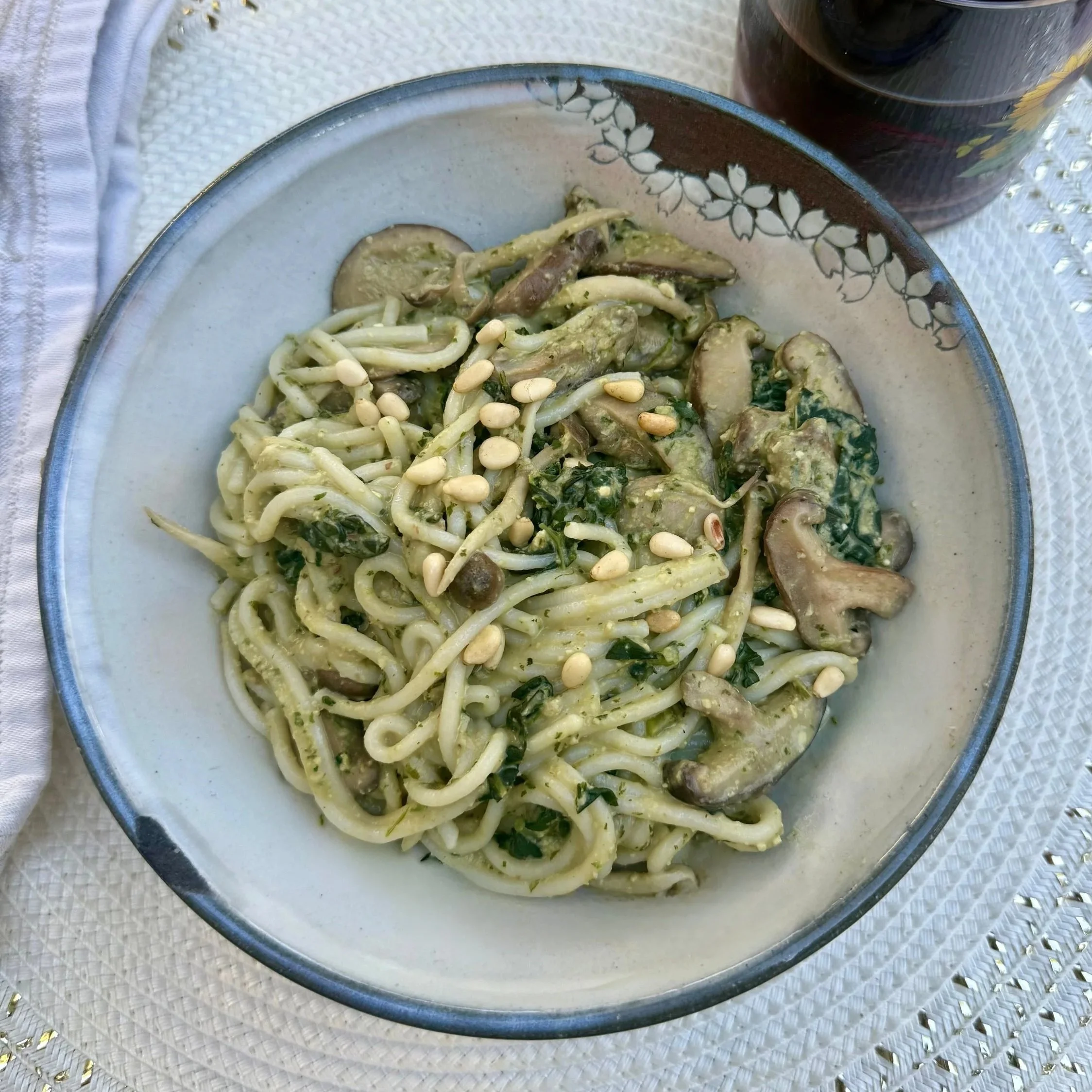 Vegan pasta tossed with creamy white bean pesto, mushrooms, greens, and pine nuts