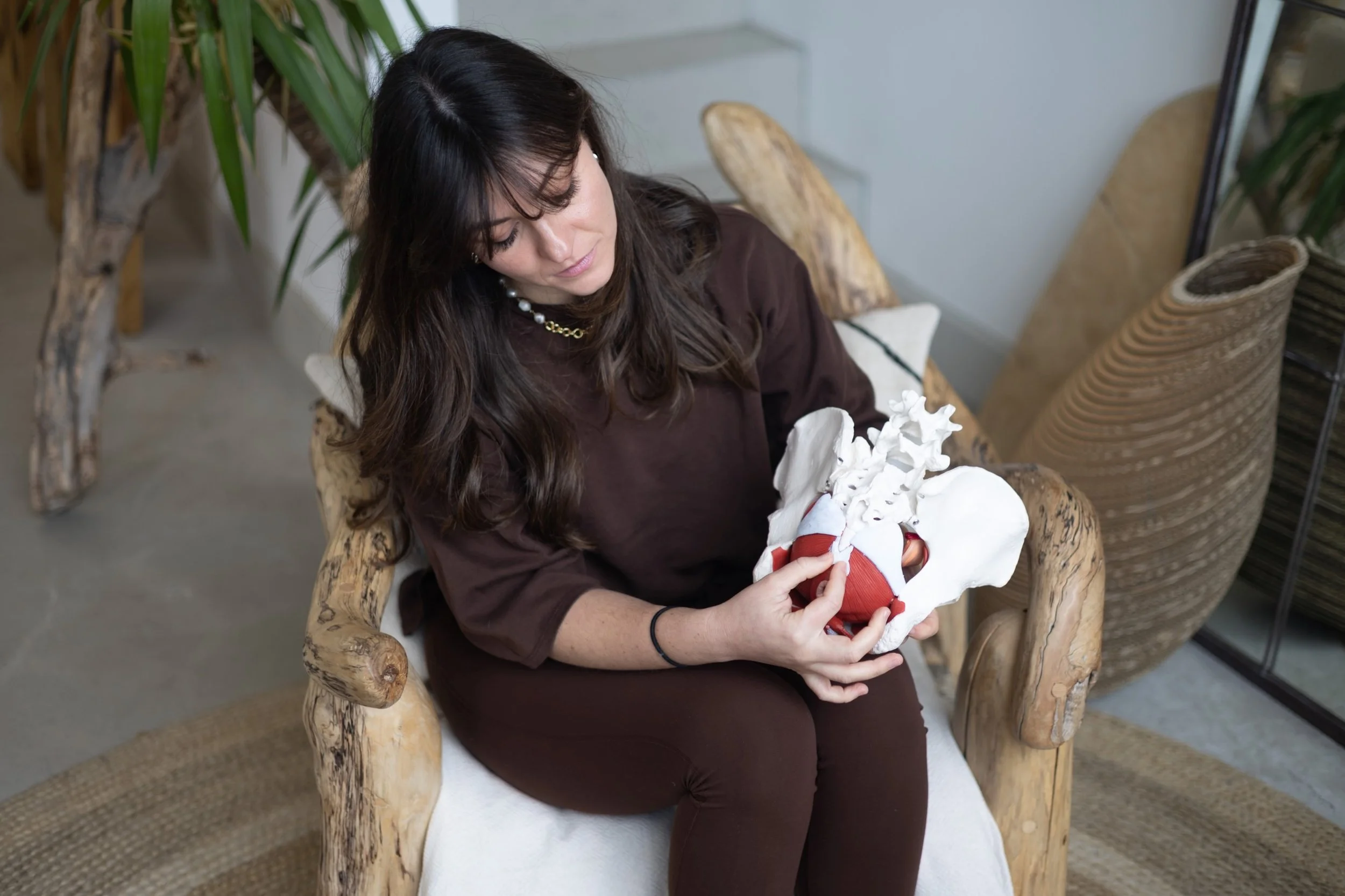 A woman sitting, a physiotherapist sitting explaning pelvic floor anatomy to a patient