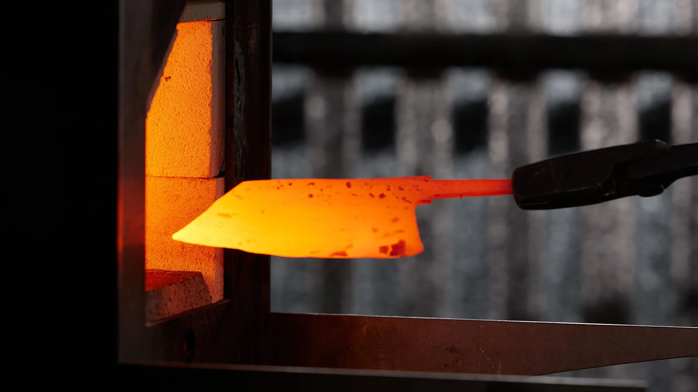 A piece of heated metal being shaped with tongs in a blacksmith forge.