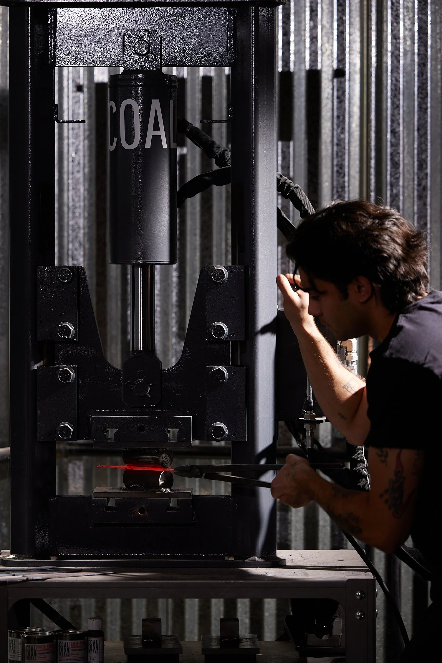A person working on a large black machinery labeled 'COAL' in a workshop or industrial setting.