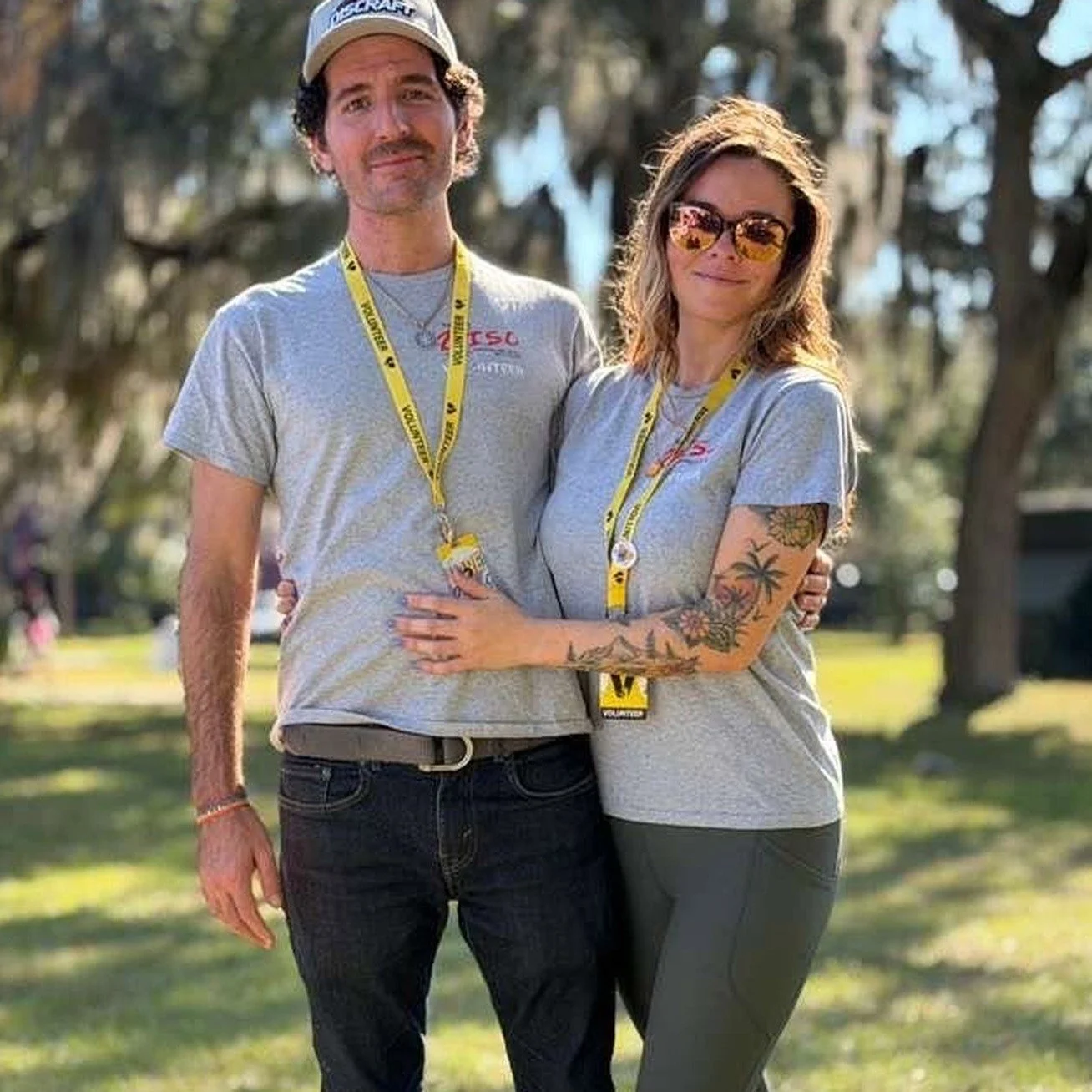 Nikki Stead outdoors at a DISC Jax event wearing a volunteer lanyard, standing with another DISC Jax volunteer.
