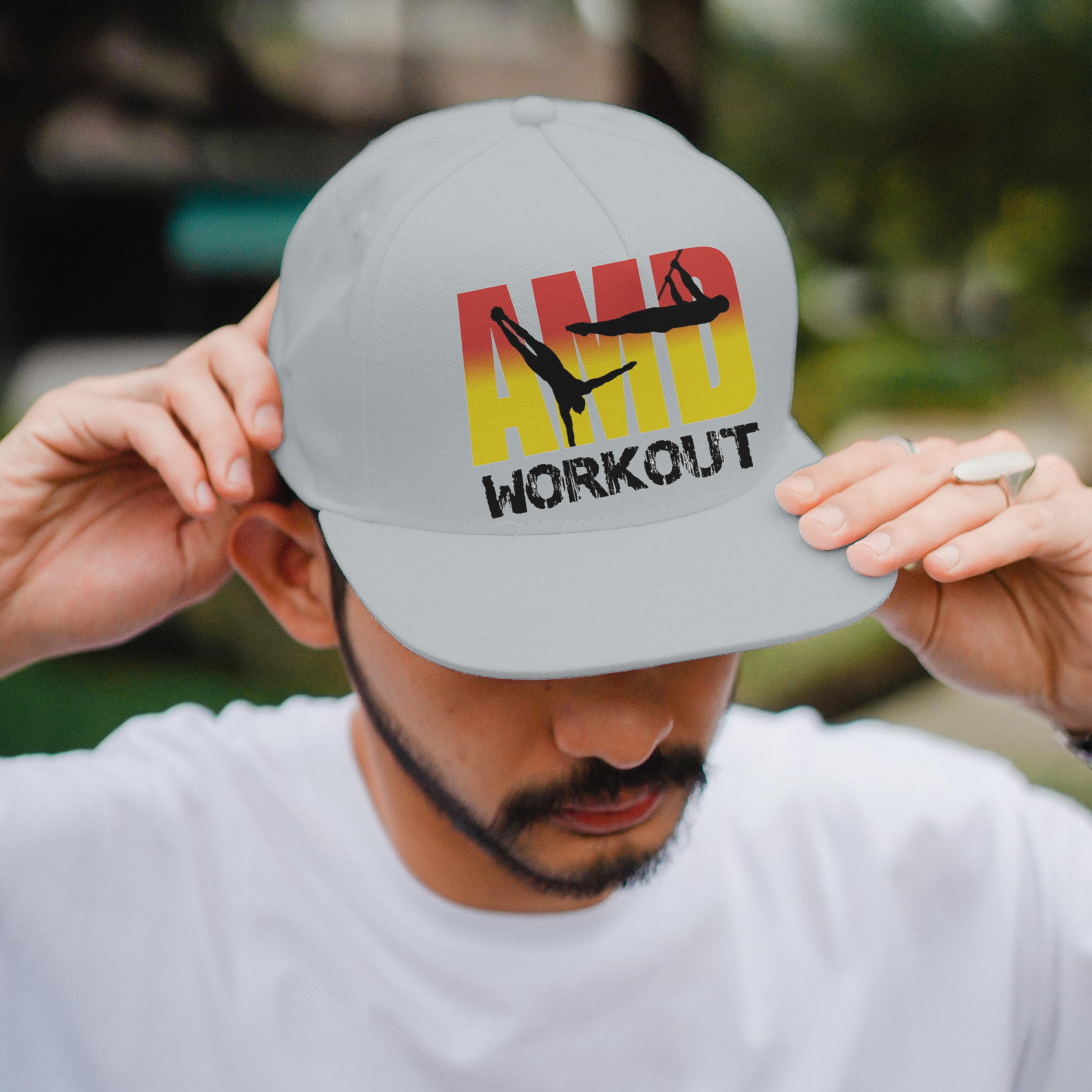 Une personne portant une casquette blanche avec le logo 'HIIT AMPD WORKOUT' et deux silhouettes de figures en suspension, dans un environnement extérieur.