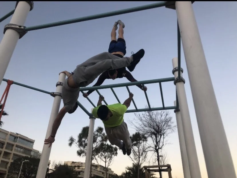 Trois athlètes font un spectacle en plein air : chacun présente sa figure de gymnastique.