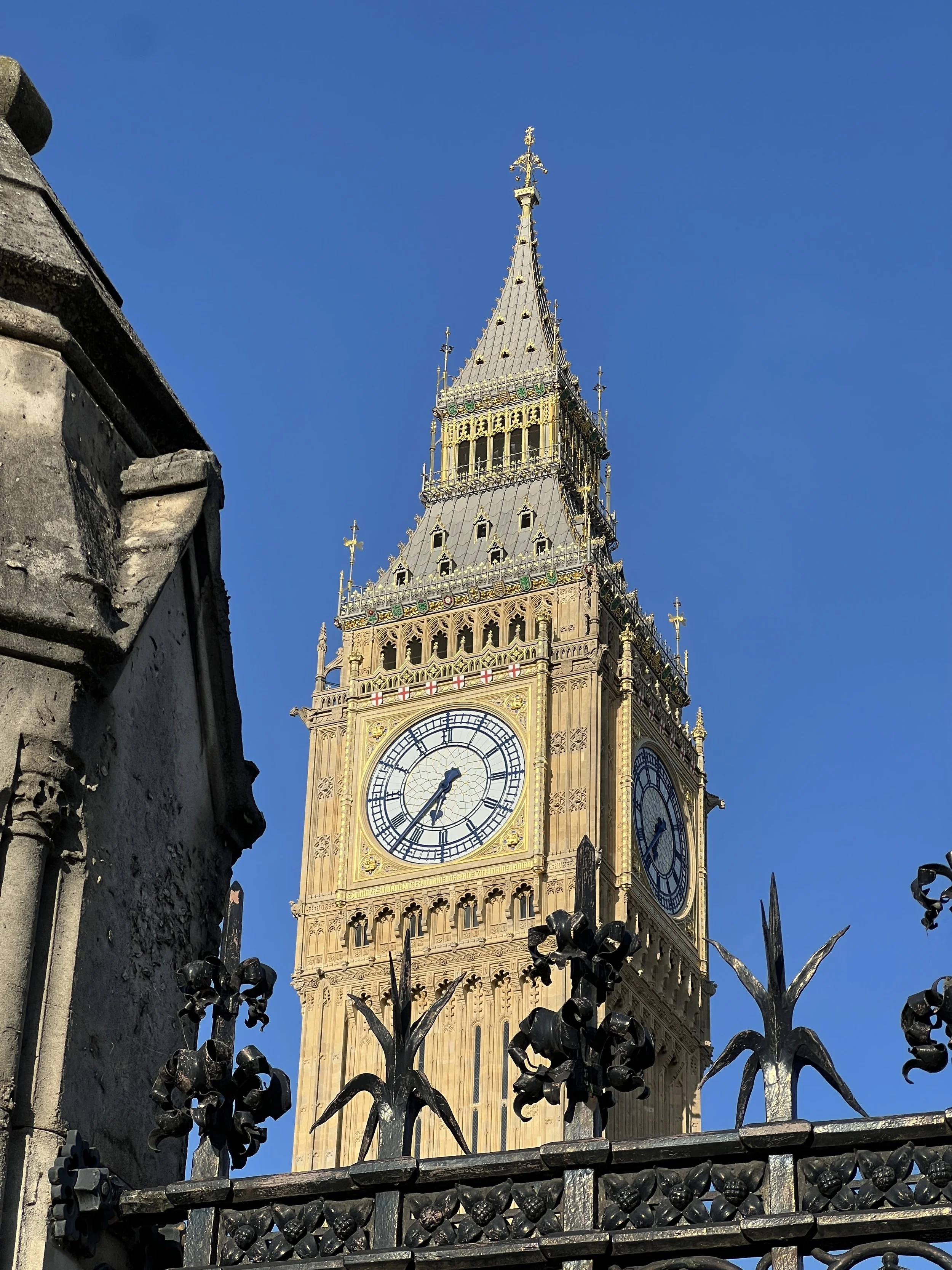 Close-up view of the Elizabeth Tower, commonly known as Big Ben, with a clear blue sky in the background. The ornate clock face is visible, showing the time as 6:32.