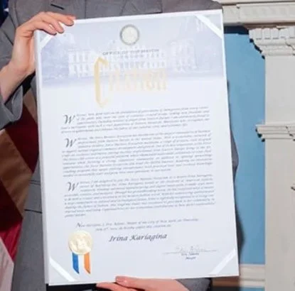 Person holding a signed certificate with gold seal and ribbon.