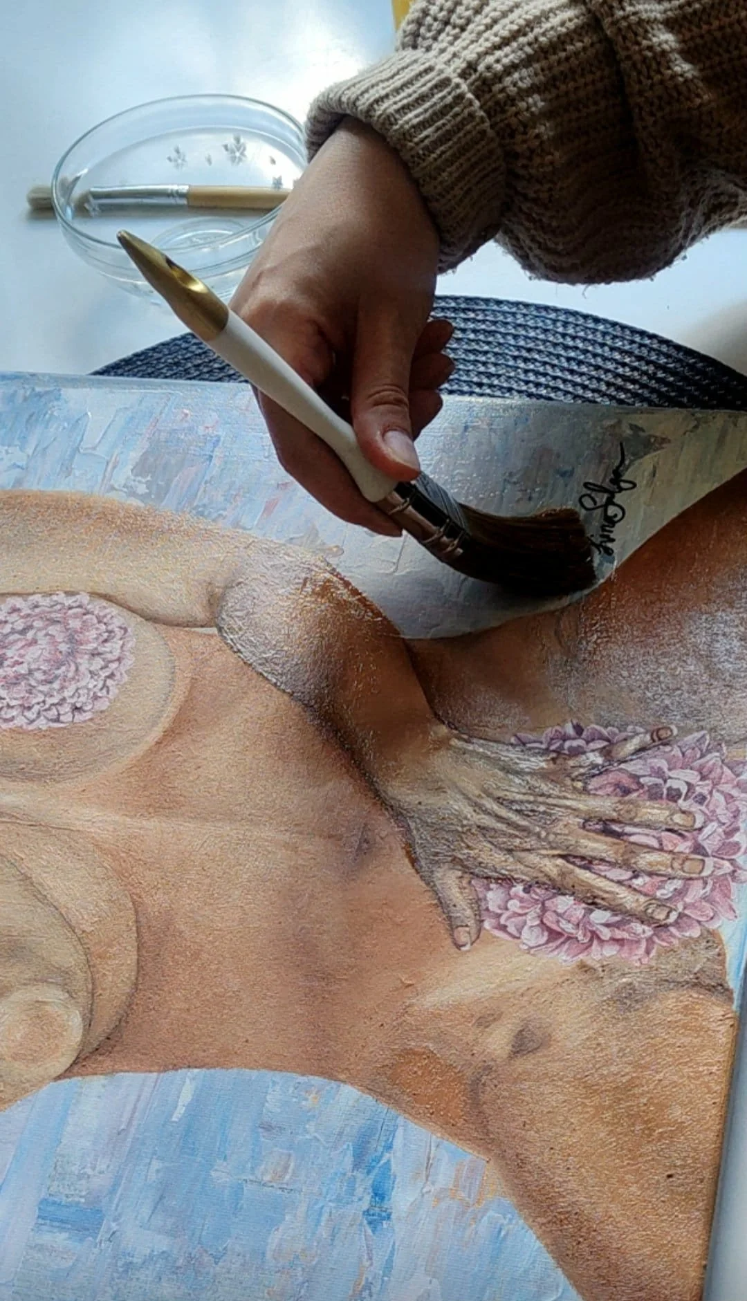 Lina Sulga applying a final layer of varnish to her finished symbolic realism painting, The Dark Feminine, highlighting brushwork, detail, and the energetic presence of the completed work.