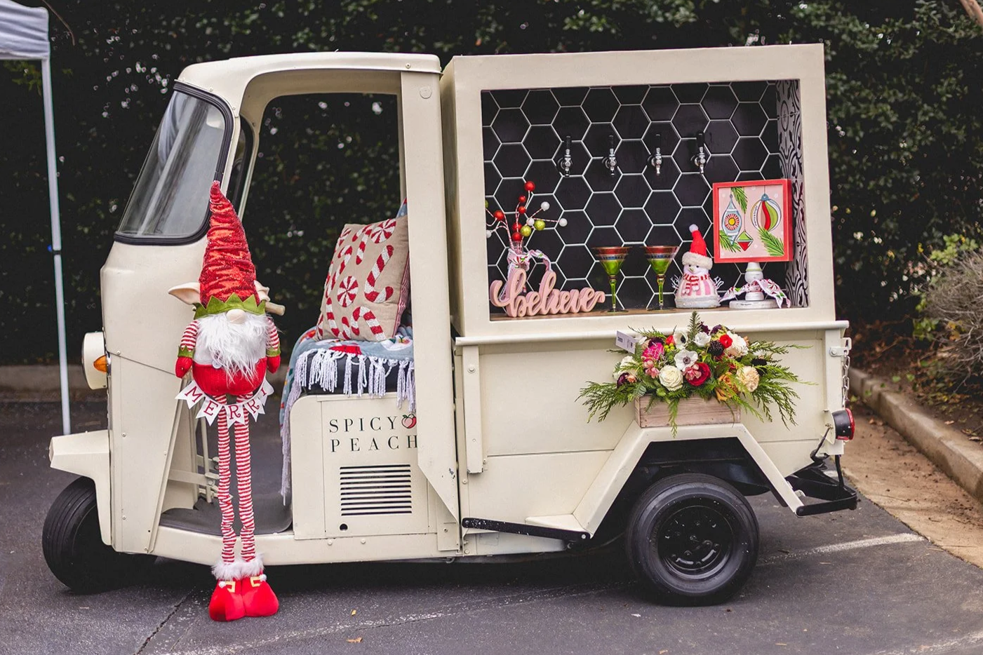 Decorated vintage three-wheeled vehicle with Christmas decorations, including a gnome, flowers, and holiday-themed ornaments.