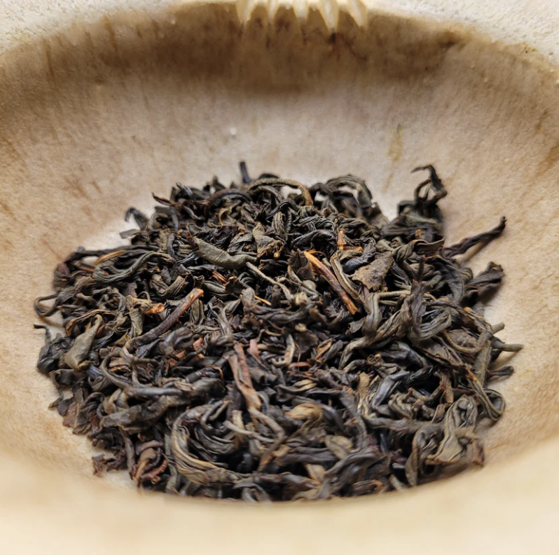 Close-up of dried tea leaves inside a wooden bowl.