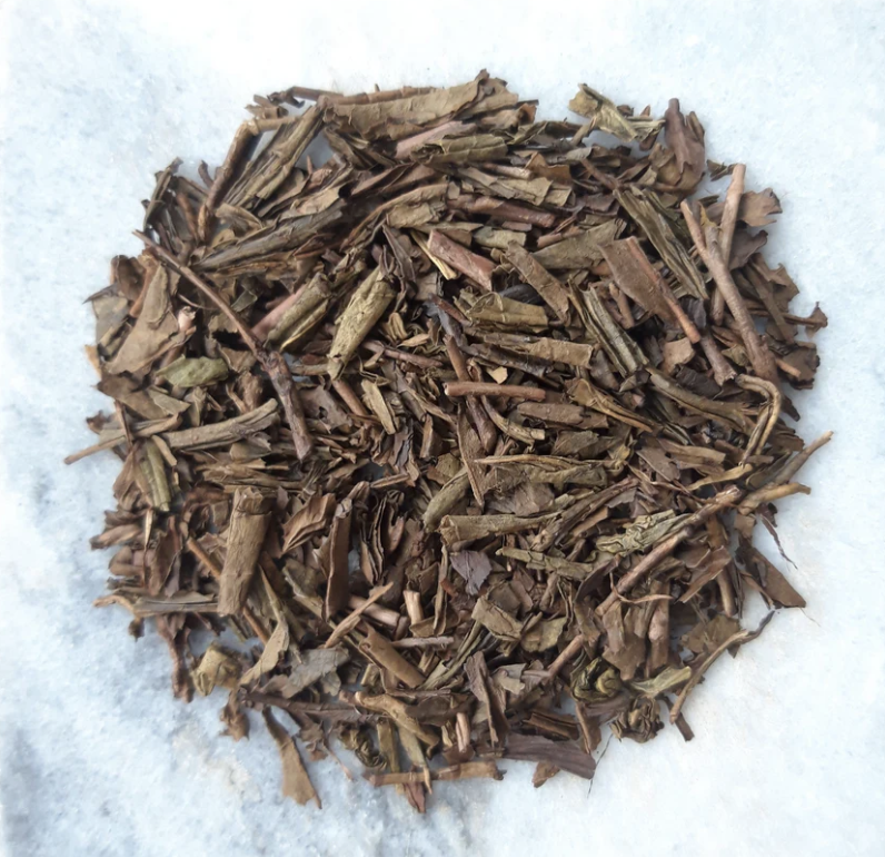 Dried brown herbal or plant material on white surface