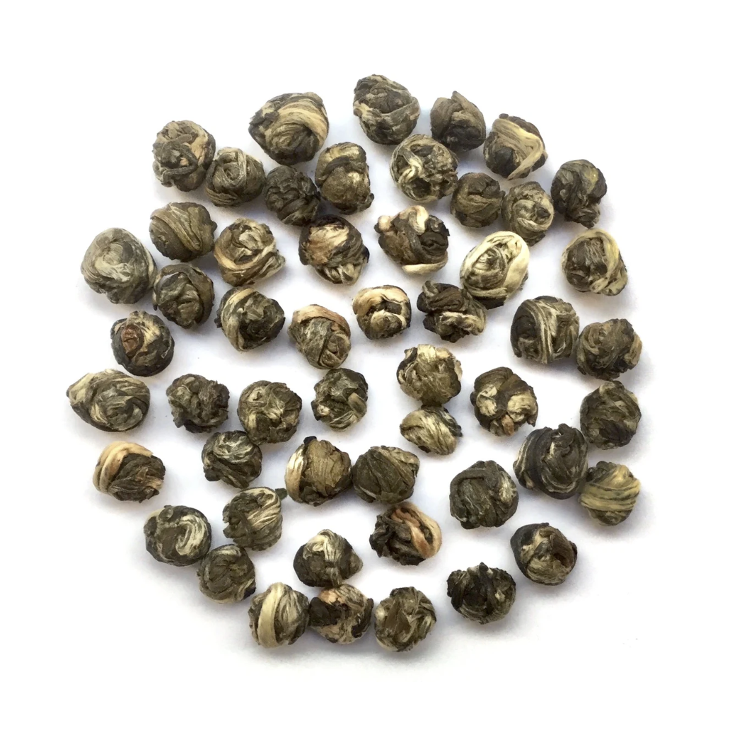 A collection of dried green tea pearls on a white background.
