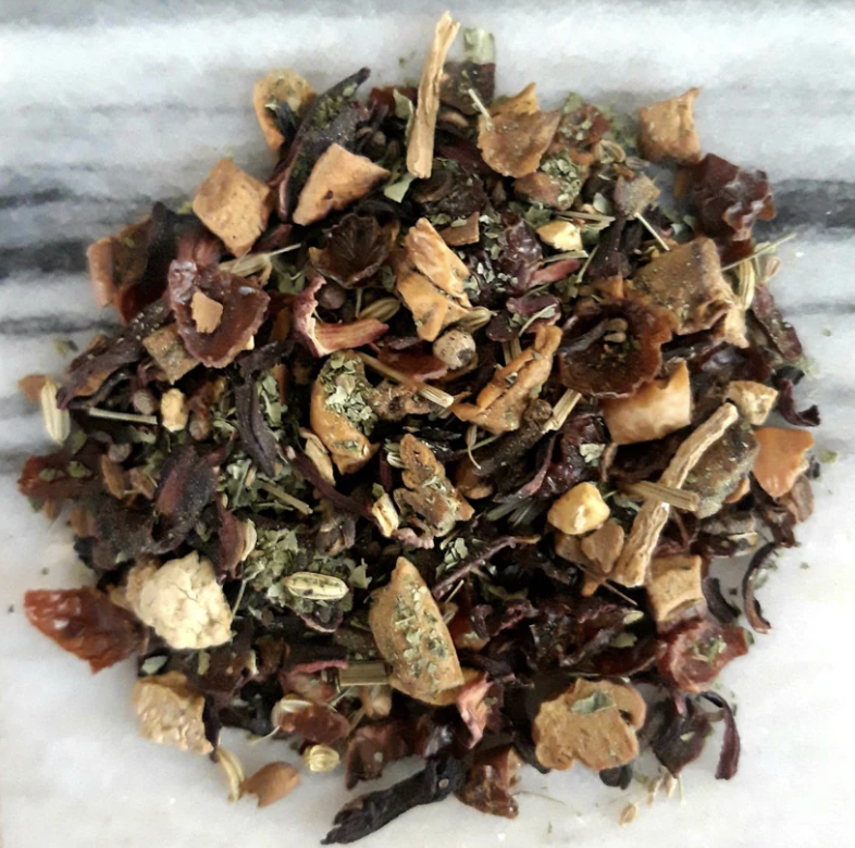 Mixed dried herbs and tea leaves on a white surface.
