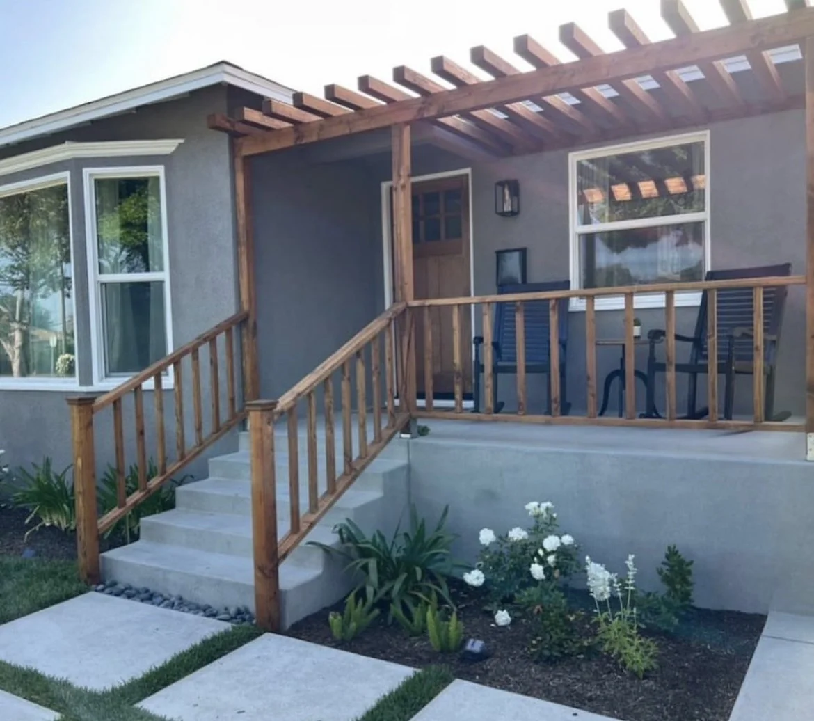 Coastal Southern California home with concrete front entry stairs, wood railings, wood pergola, and wood front door