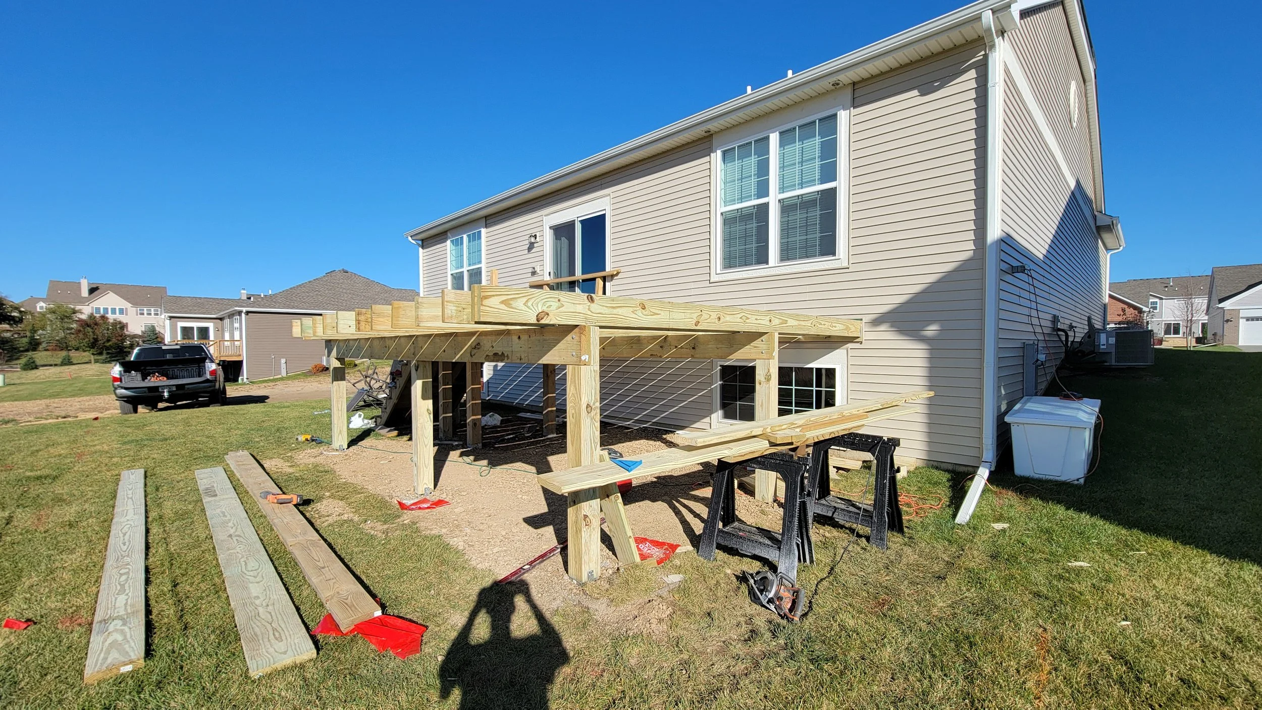 Construction of a wooden deck at the back of a beige house on a sunny day