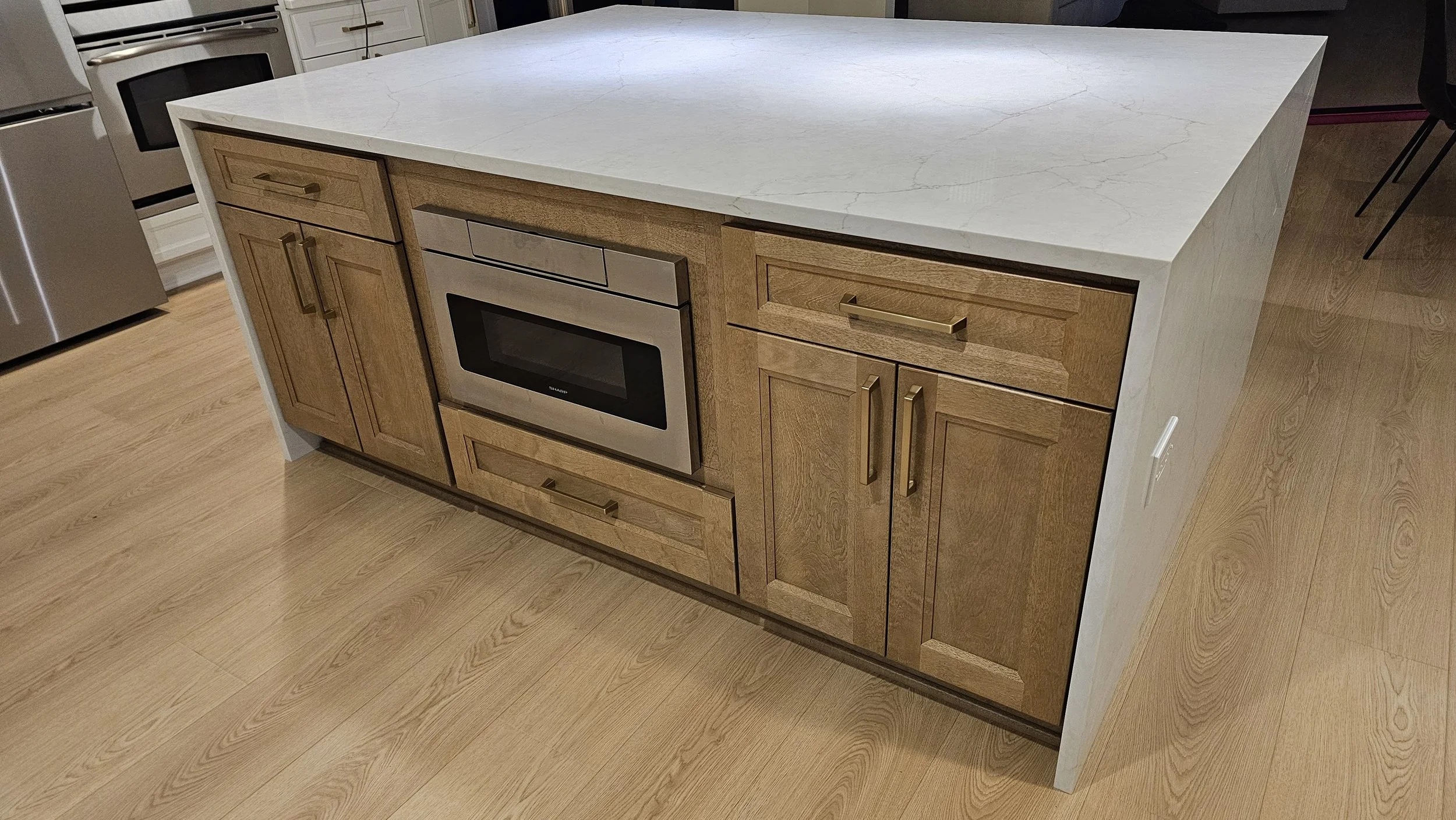 Kitchen island with wooden cabinets and a built-in oven, topped with a white marble countertop.