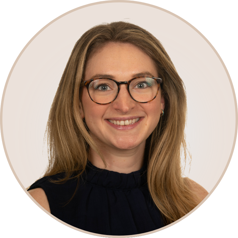 A woman with glasses and long light brown hair smiling at the camera.