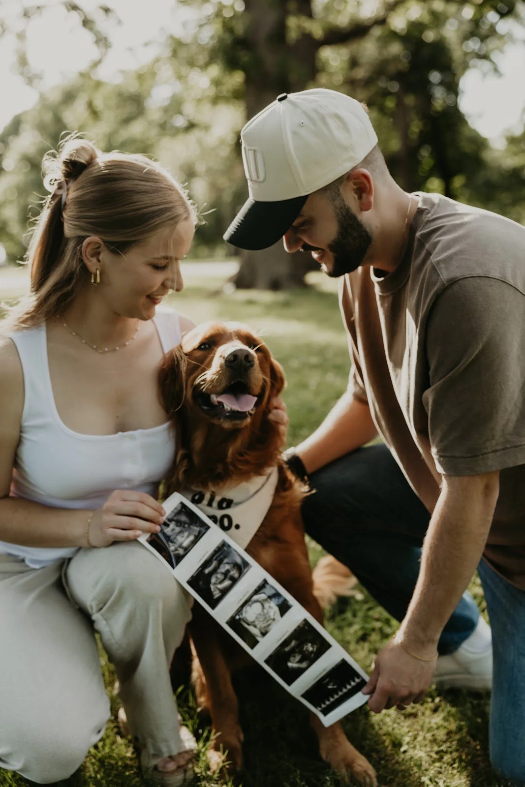 Charleigh and her husband with their Golden Retriever, Stark, holding baby ultrasound photos
