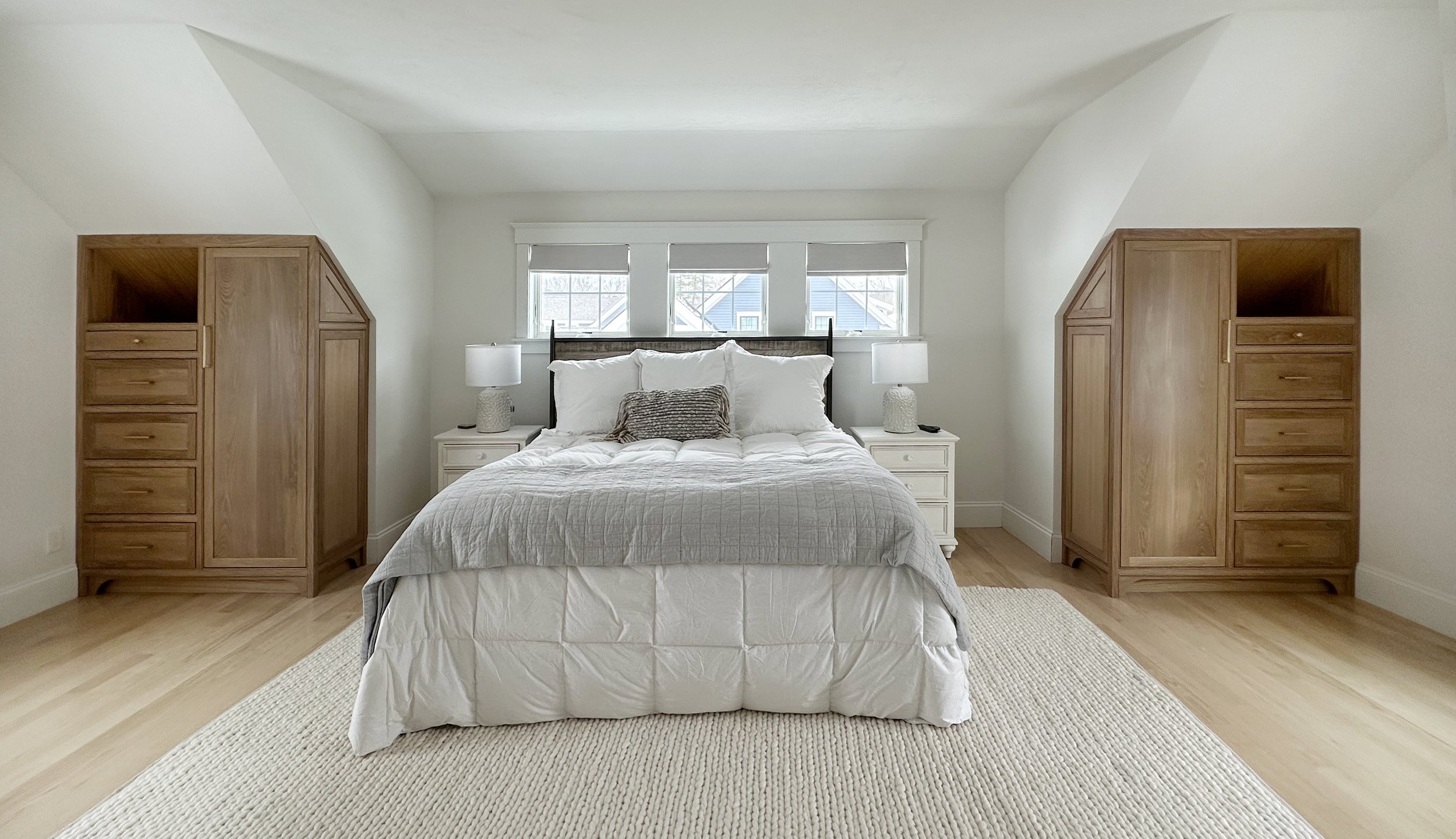 Custom white oak bedroom armoires designed to expand closet storage in a Newburyport, Massachusetts home.