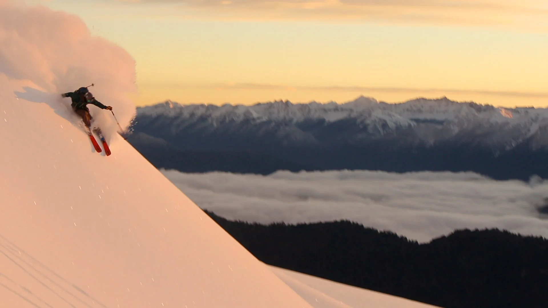 Backcountry skier in a cloud of powdery snow in Patagonia, with Lake Nahuel Haupi in the background.
