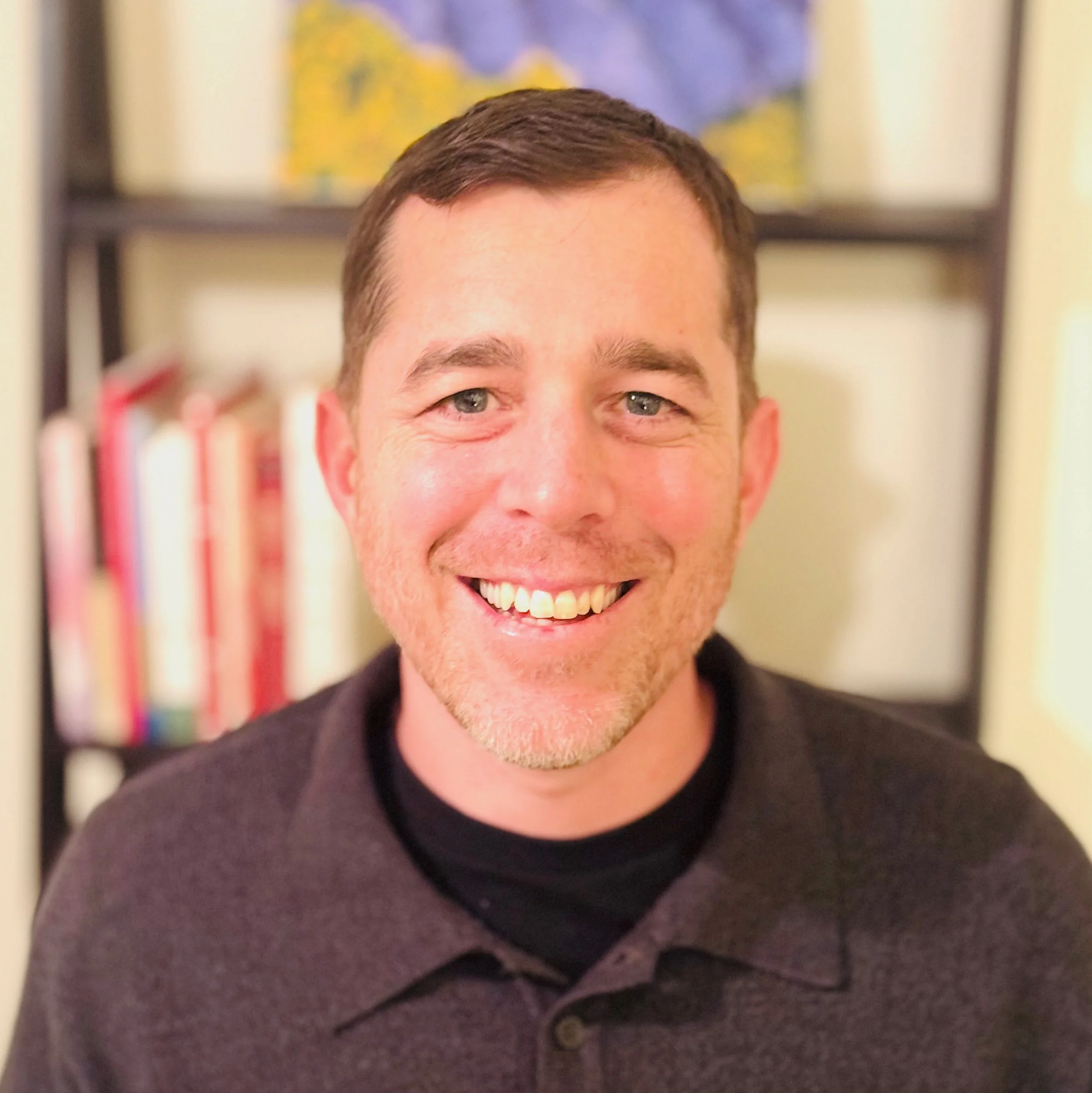 man smiling in black shirt.