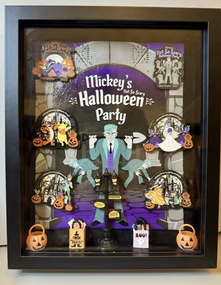 Halloween display featuring pins and decorations with Mickey Mouse theme. The central figure is a gray-haired man in a teal suit, holding a cane. Surrounding him are various Halloween characters and themed pins, including pumpkins, ghosts, and other 