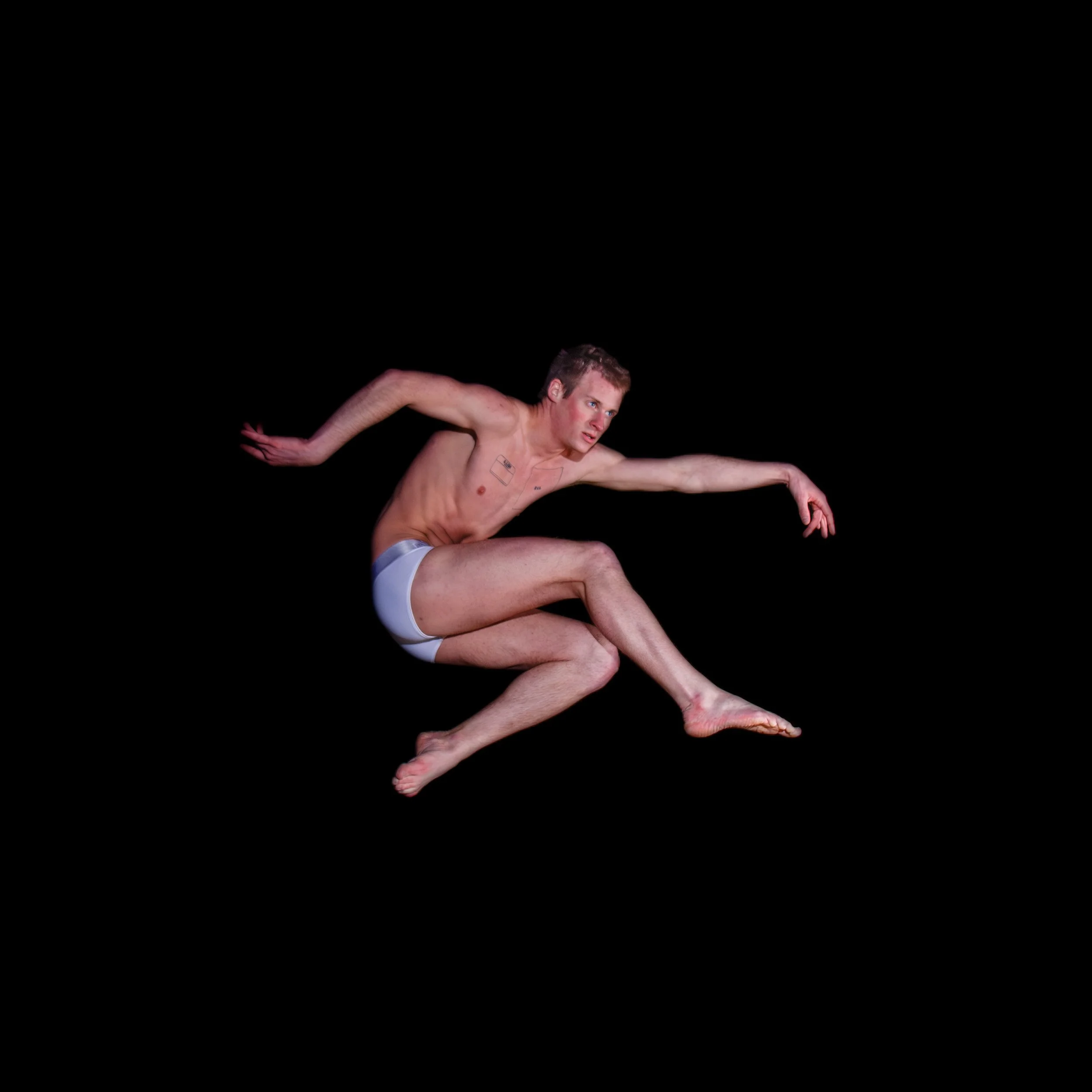 A man in underwear appears to be mid-air against a black background, with his limbs extended and a focused expression.