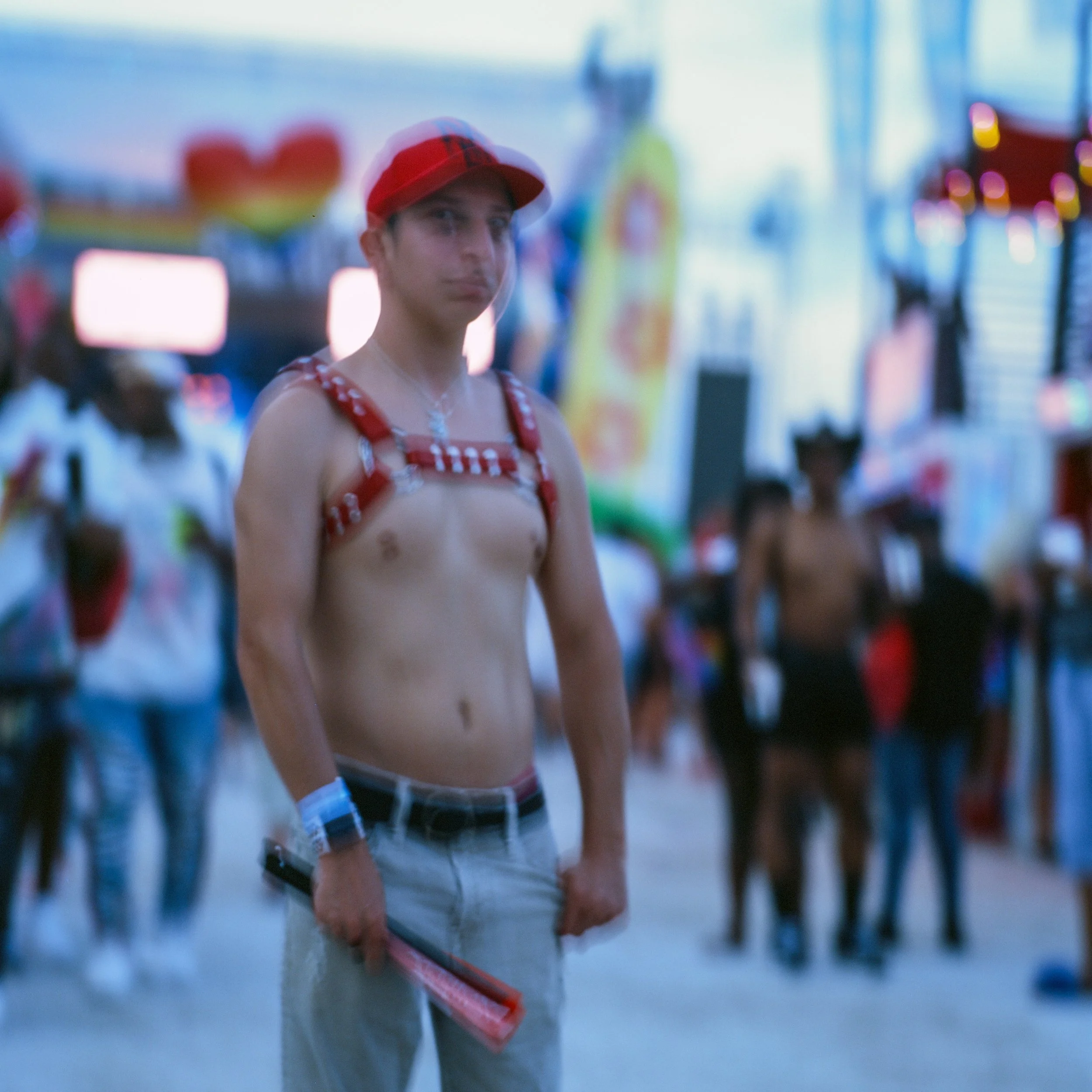Person wearing a red hat and harness holding a fan at an outdoor event or festival.