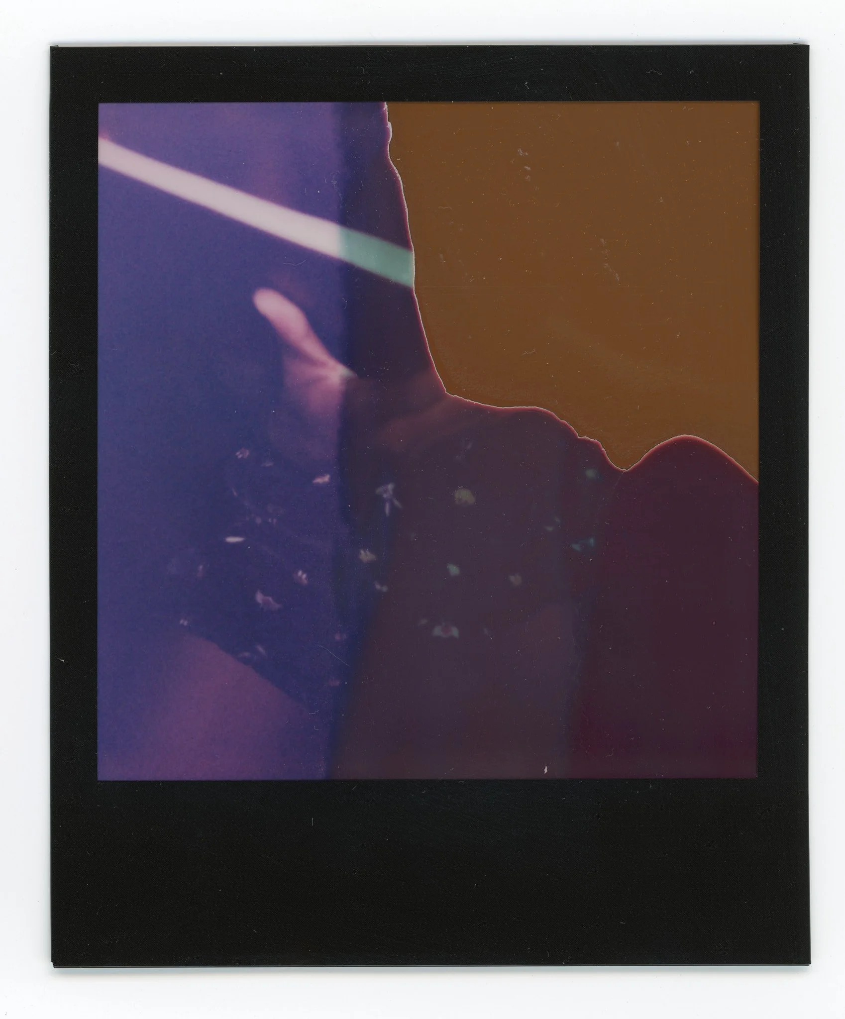An instant film photograph with a black border, exhibiting abstract, colorful patterns and textures.