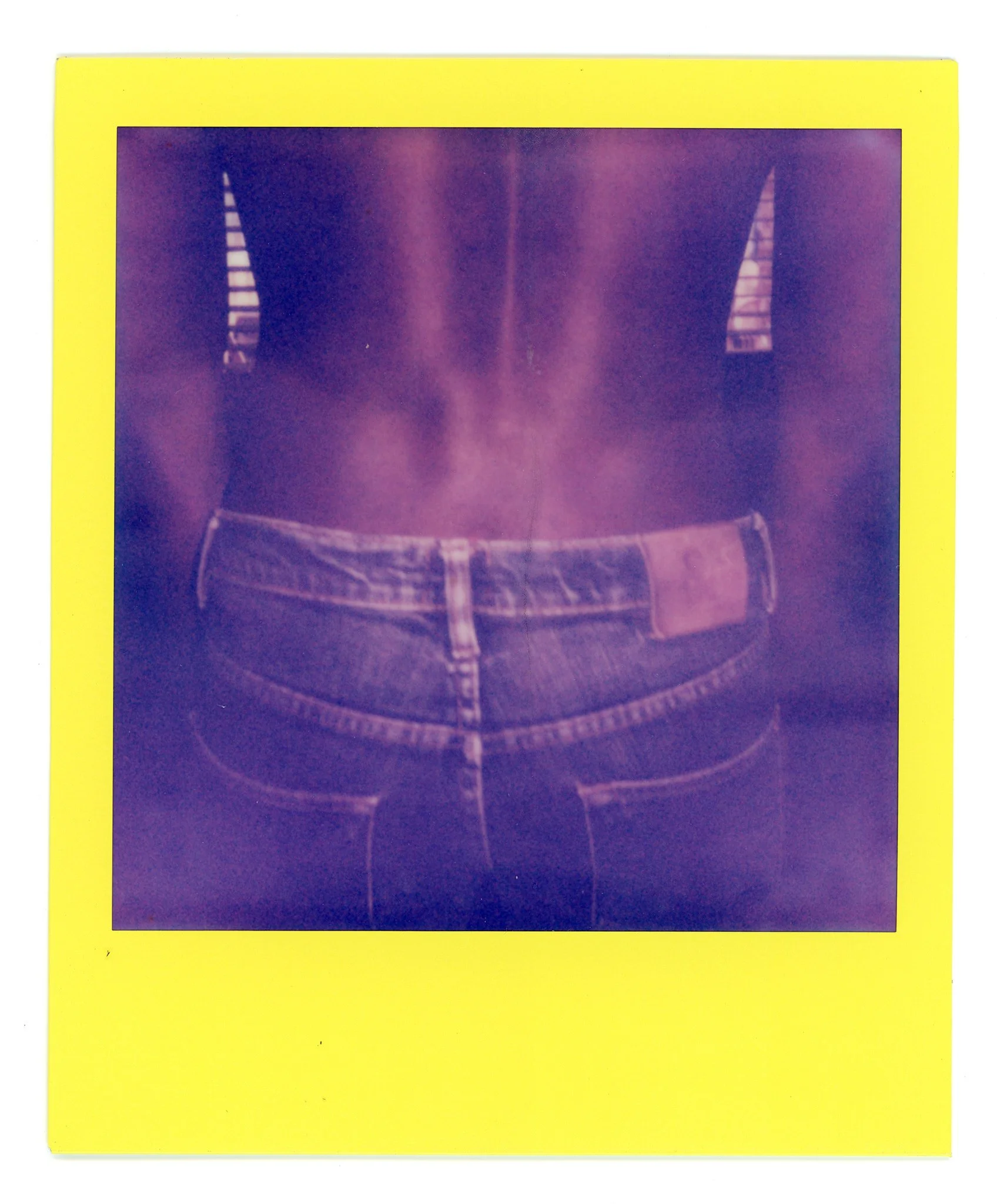 Close-up of a person's torso wearing a black shirt and blue jeans with a leather patch on the back pocket.