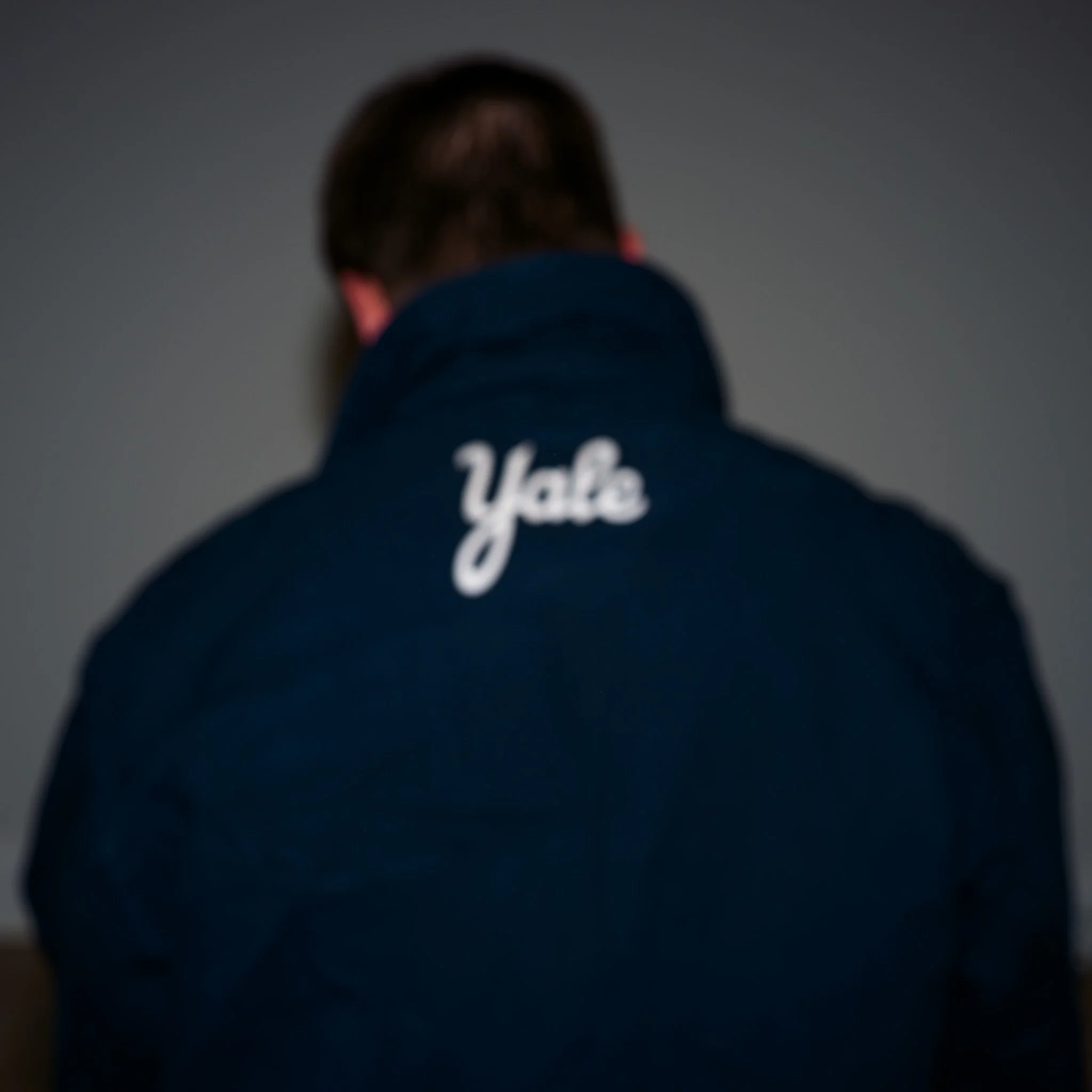 Back view of a person wearing a dark jacket with 'Yale' embroidered on the back.