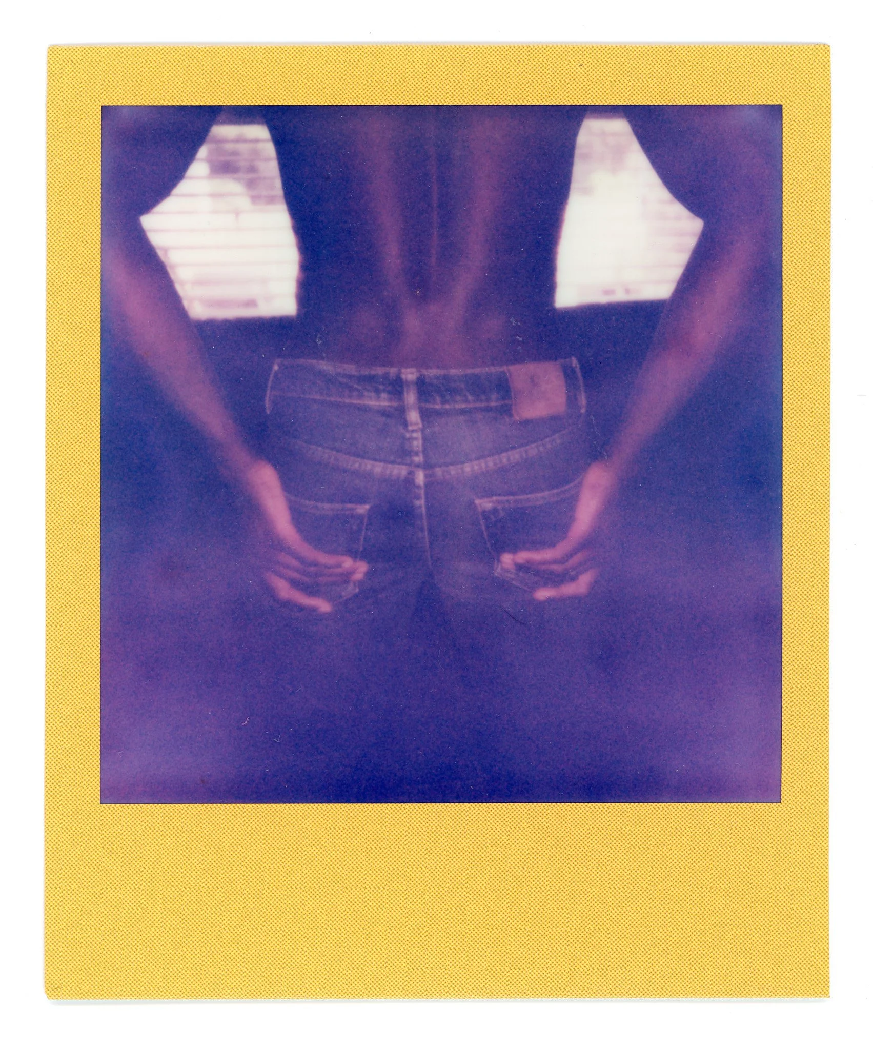 Back view of person wearing blue jeans with hands on hips, no shirt, with a yellow border around the photo.