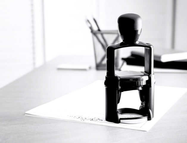A black rubber stamp on a white sheet of paper on an office desk.