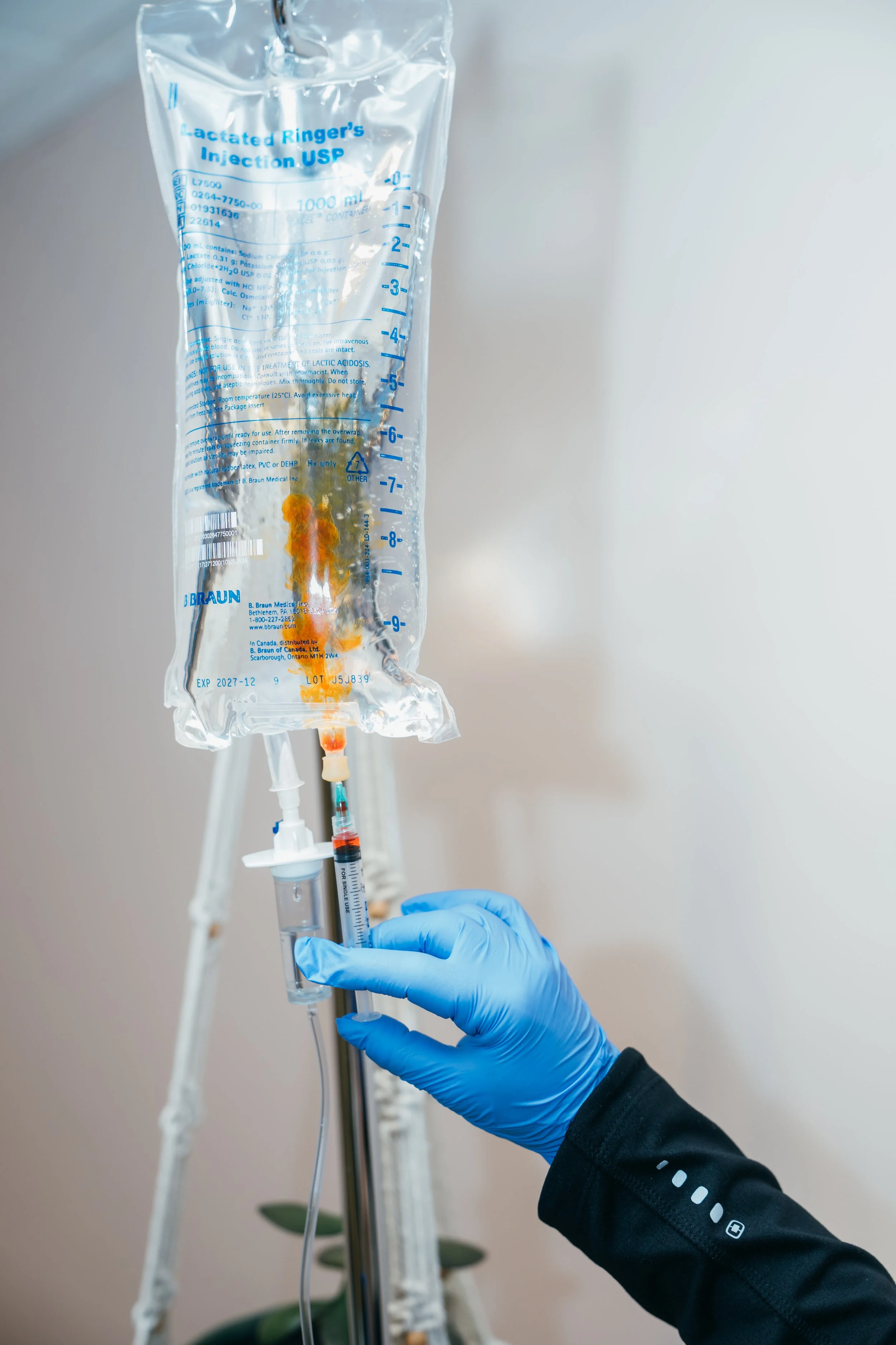A woman in a hospital bed smiling as a healthcare worker with gloves draws blood from her arm.