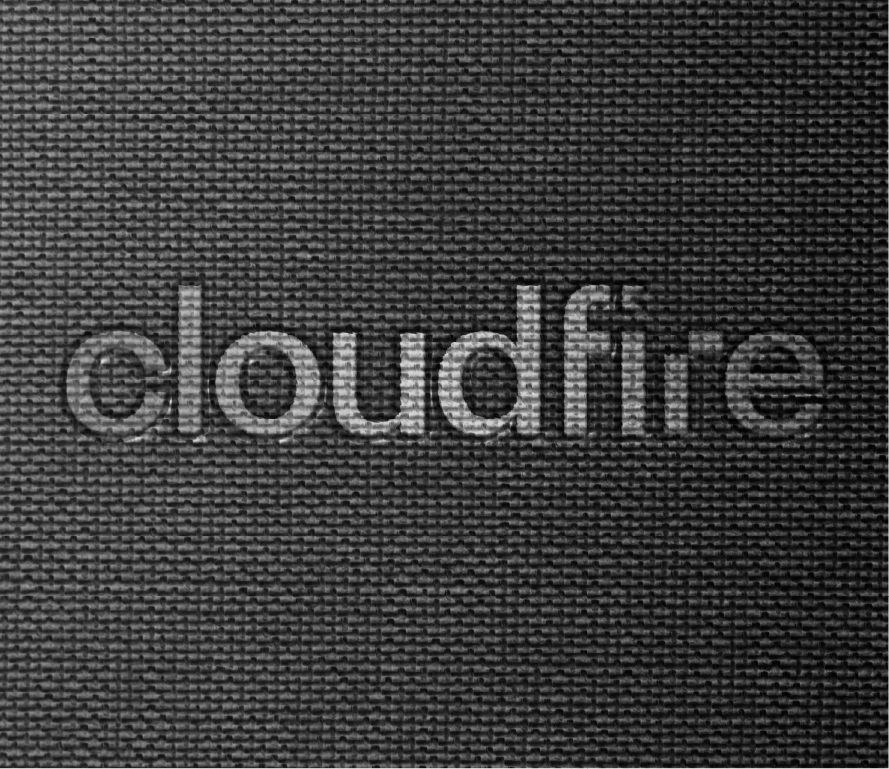Close-up of a textured black fabric with the word "dcloudfire" embroidered in gray thread.