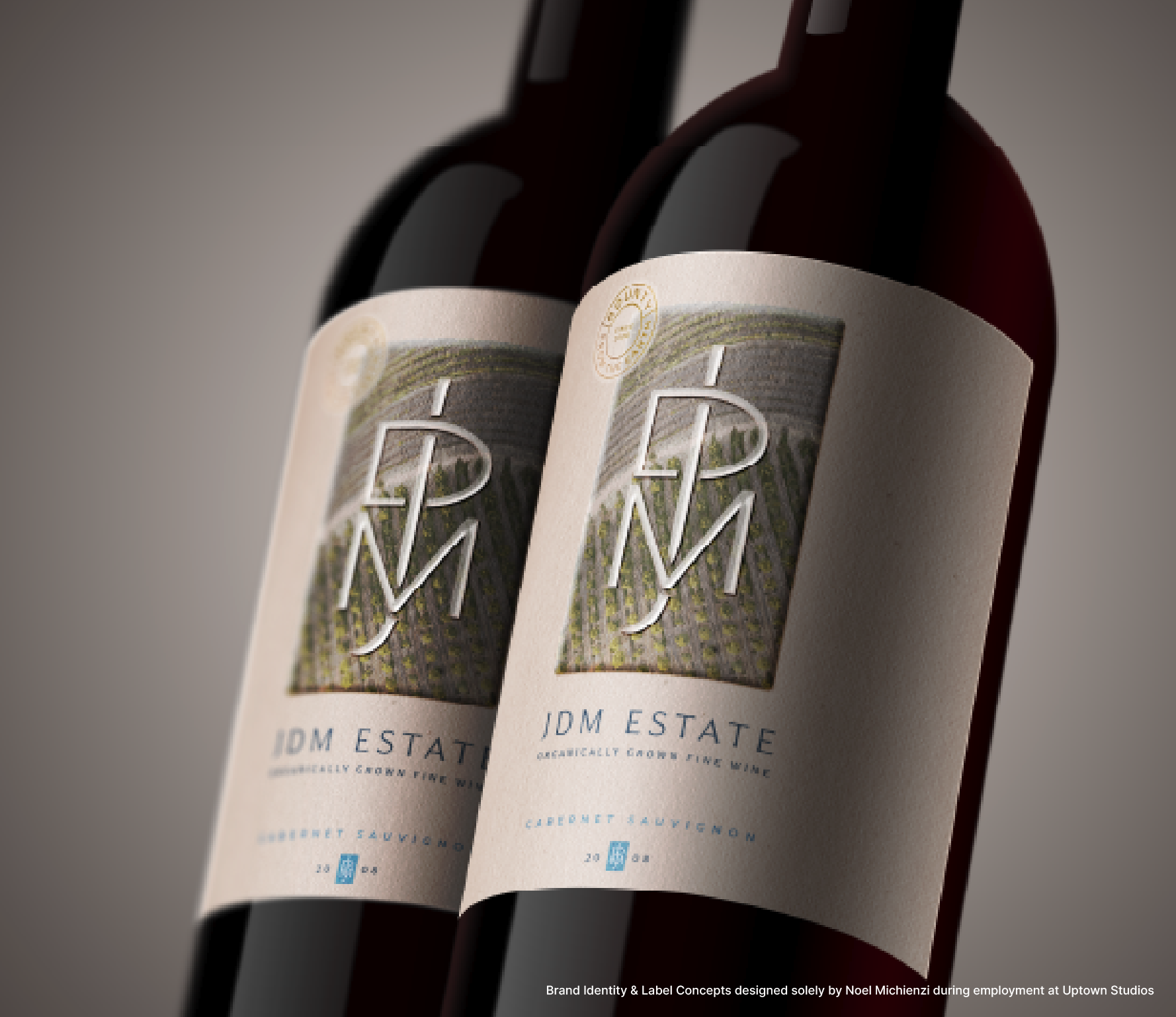 Two bottles of IDM Estate Cabernet Sauvignon wine tilted against a neutral background.