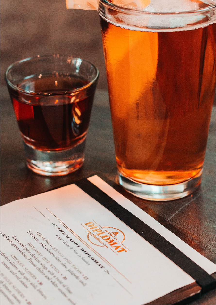 A menu and two glasses of different types of beer on a dark table.