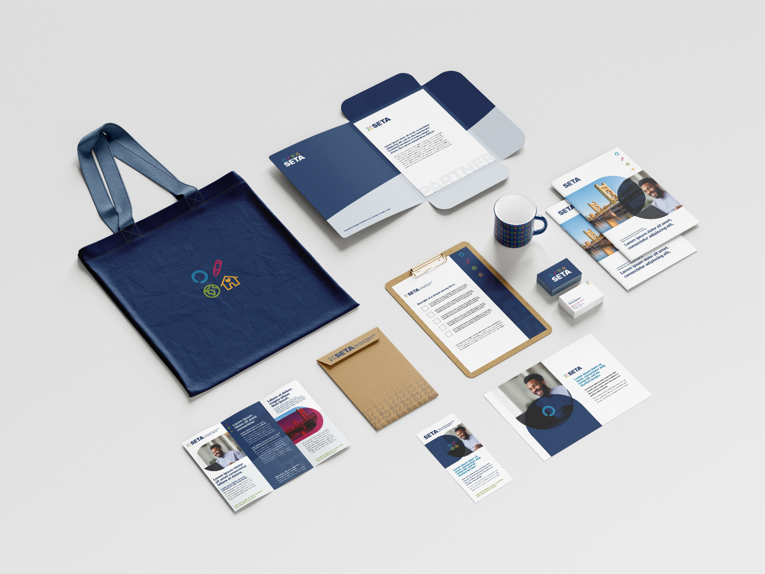 Collection of branded business stationery and promotional materials including a navy tote bag, brochure, flyers, business cards, notepad, pen, and mug, all featuring the SETA logo and branding in navy, white, and colorful icons on a white background.
