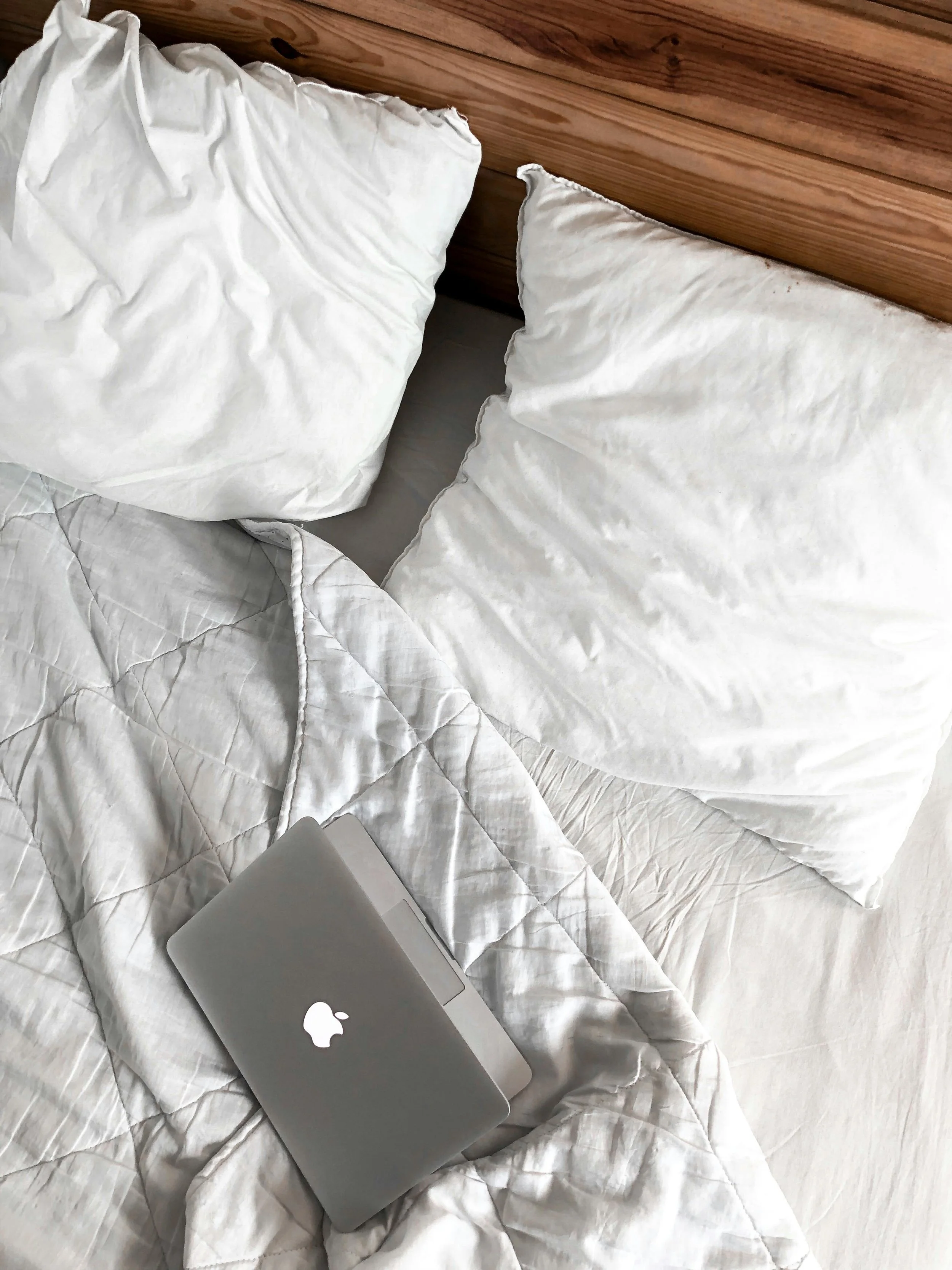 Laptop on a bed representing rest, self-care, and recovery from stress and burnout