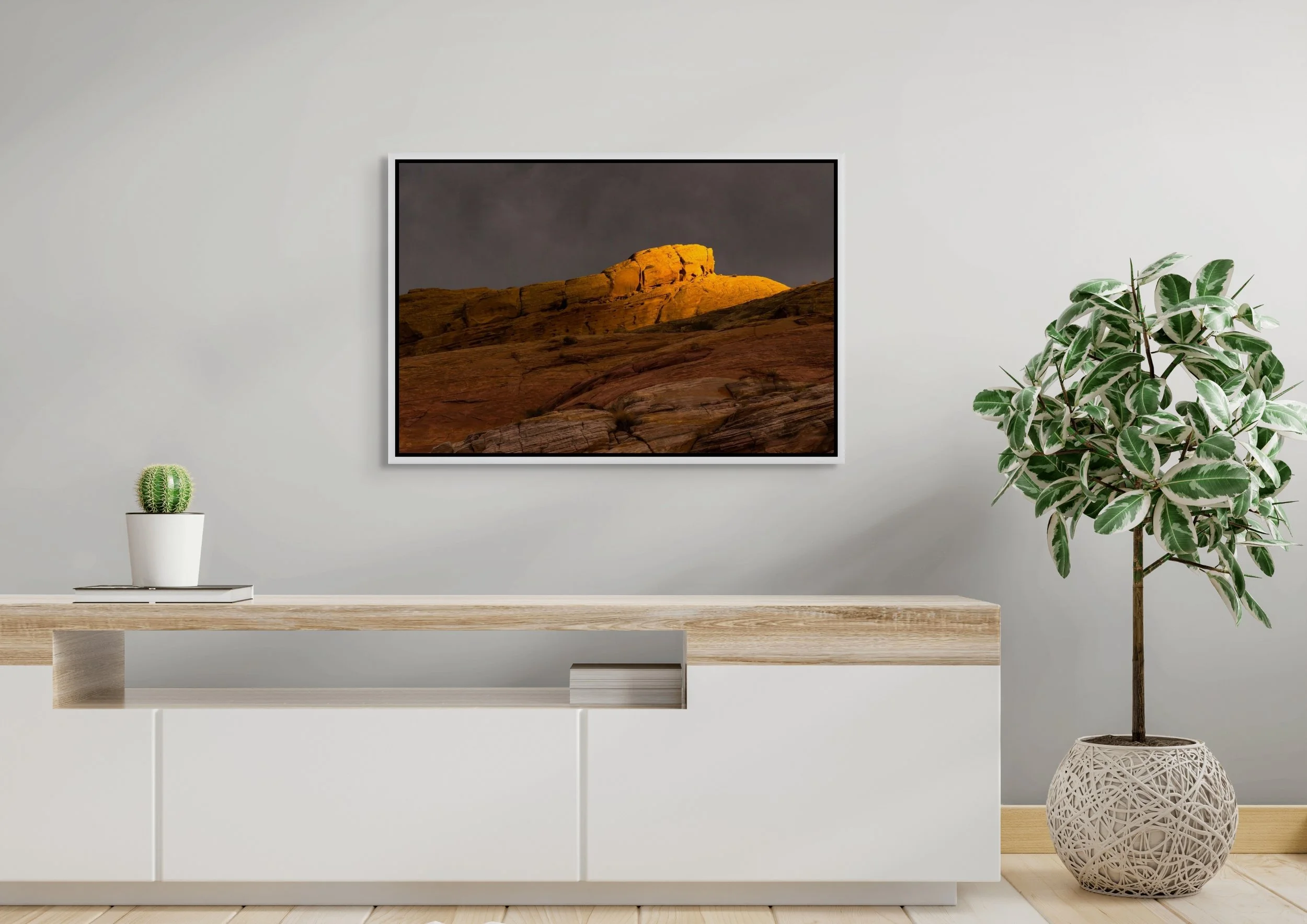 Where Light Lingers, floating White frame, mounted above a minimalist white sideboard with potted plant in a clean, bright interior.