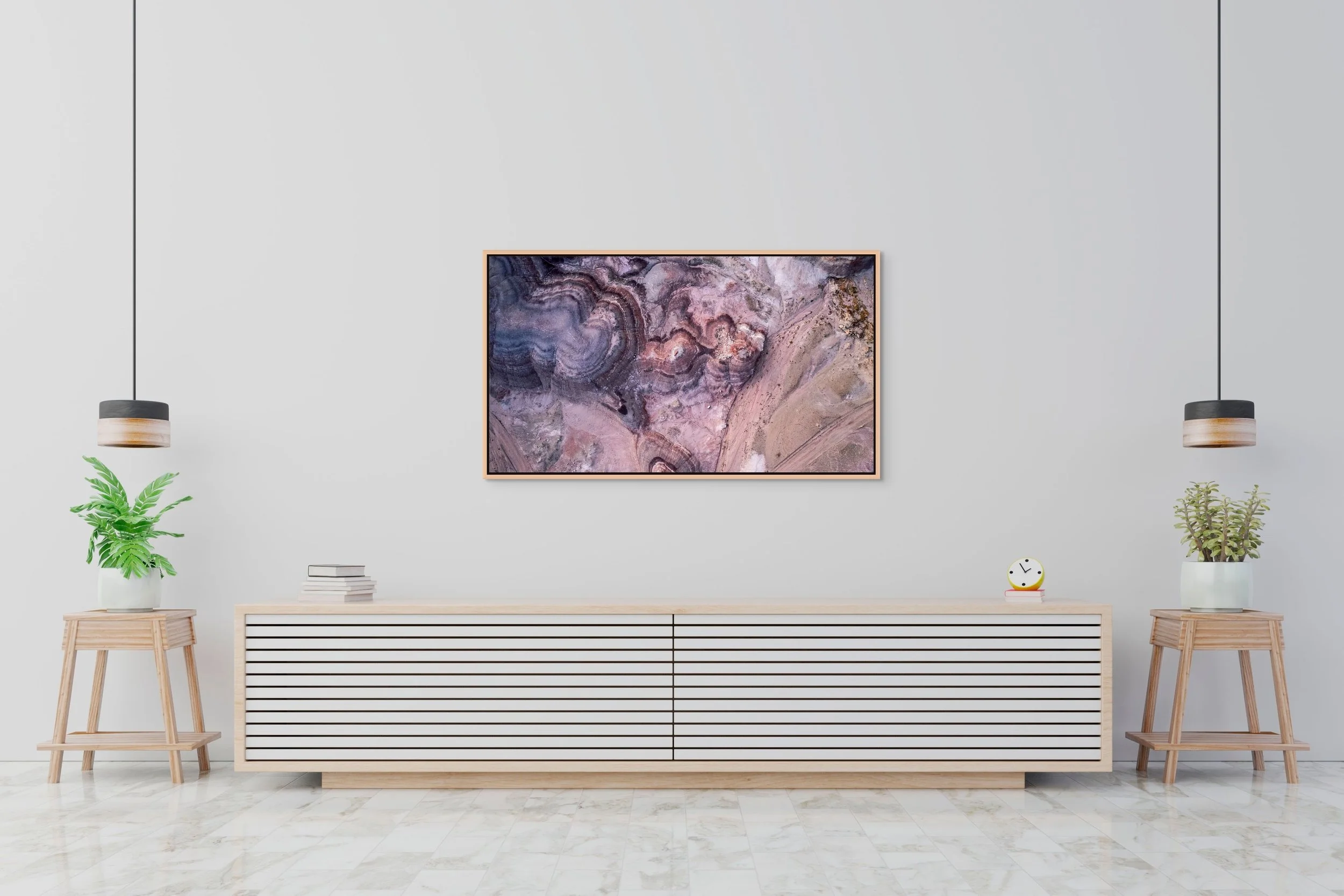 Small in Time — aerial bentonite-hill patterns in mauve and cream, framed in natural oak floating wood frame on a minimalist white credenza.