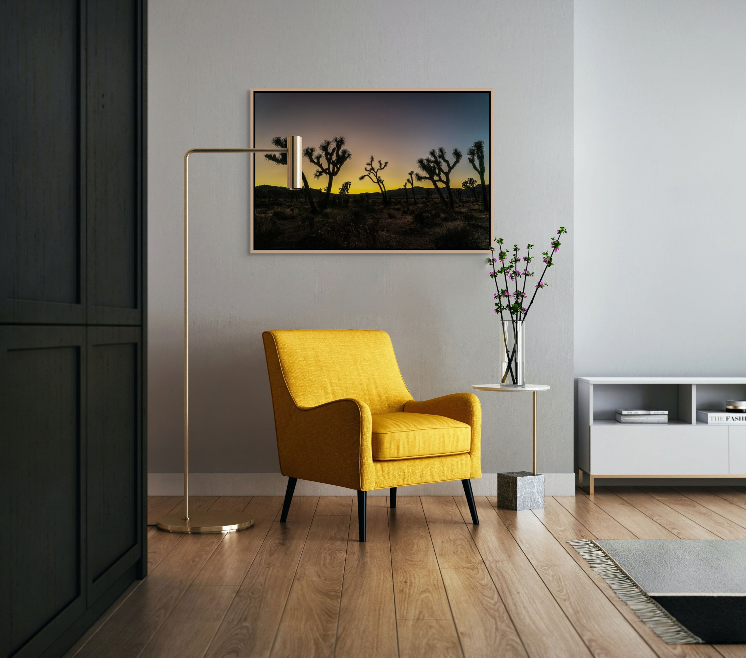 Desert Sentinels — Joshua Tree silhouettes at gold dusk, framed in natural oak floating wood frame, shown in a moody reading corner with dark paneling and a mustard lounge chair.