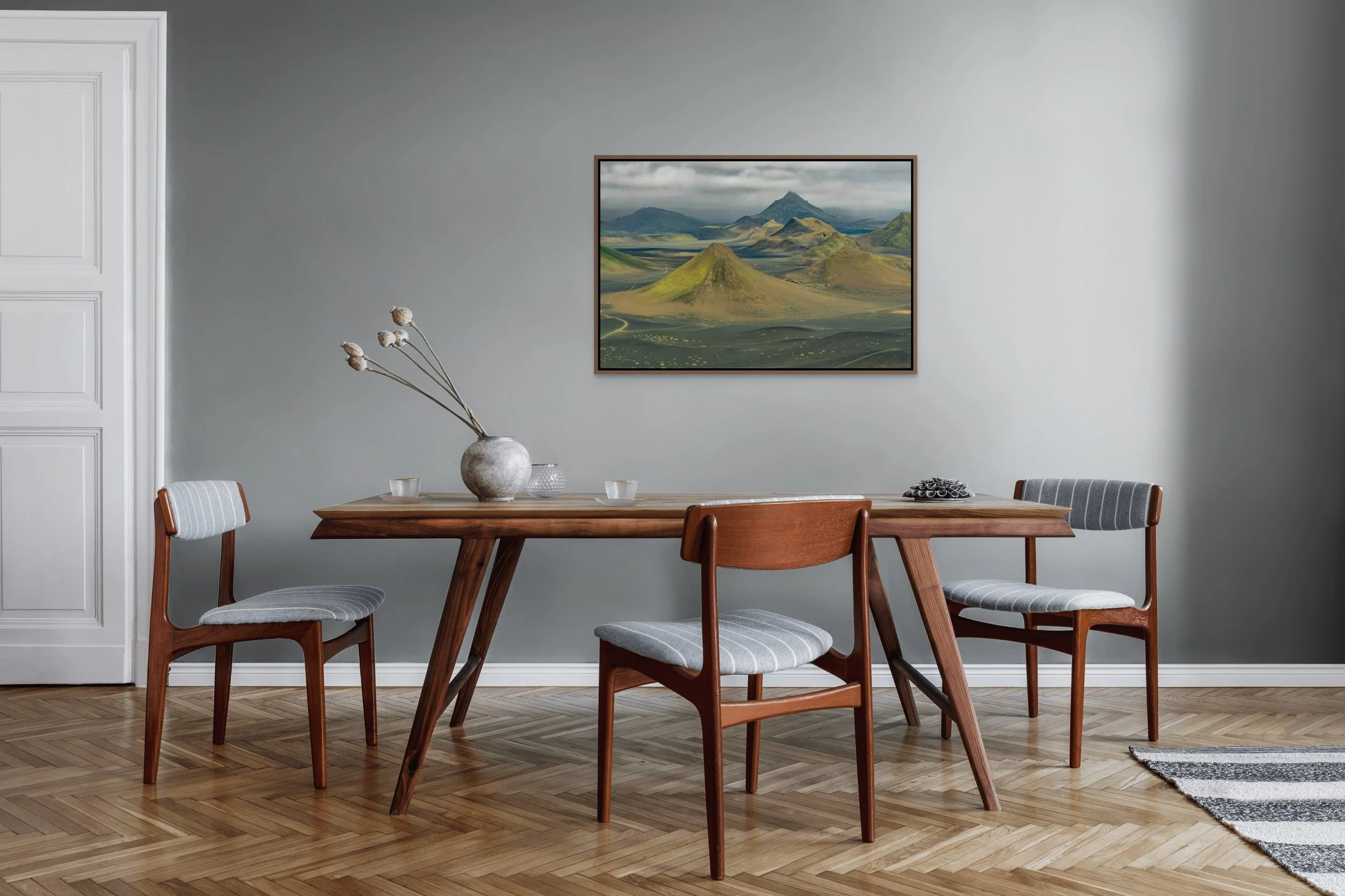 Where Earth Dreams in a floating Walnut frame, styled over a wood dining table in a soft gray dining room.