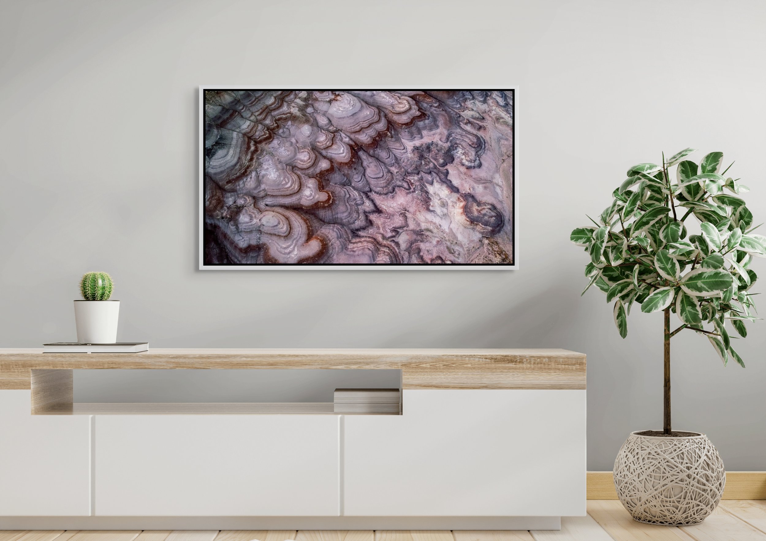 Layers of Time framed in floating wood — white; modern sideboard and potted plant beneath the artwork.