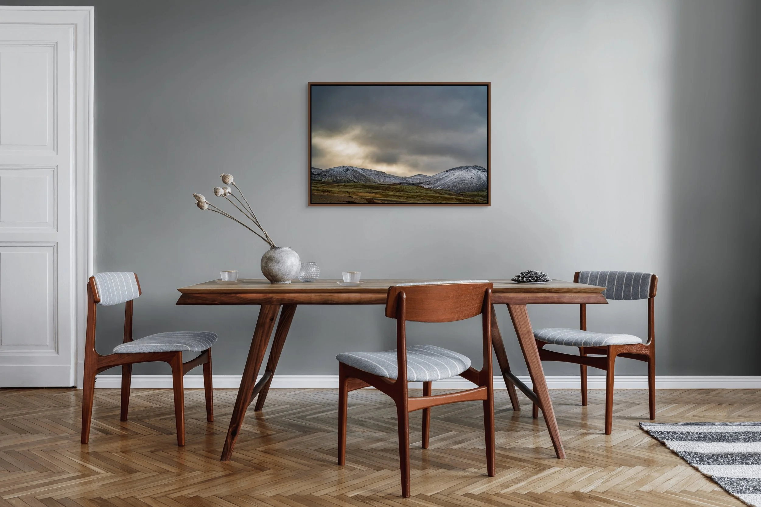 Snow, Then Silence in a floating Alder Brown frame, above a modern dining set against a soft gray wall.