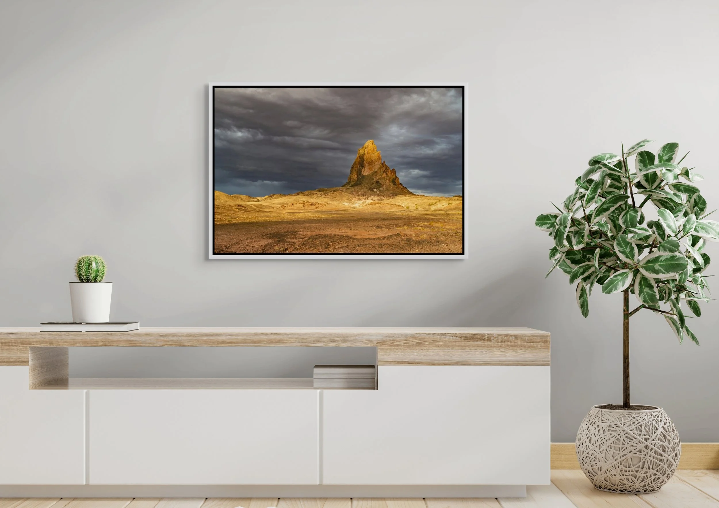 Sentinel of Stone in a floating White frame, mounted above a clean white sideboard with potted greenery.